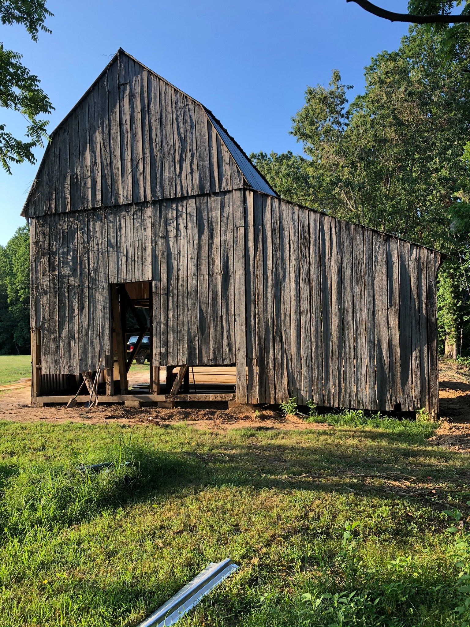 An old wooden barn is sitting in the middle of a grassy field.