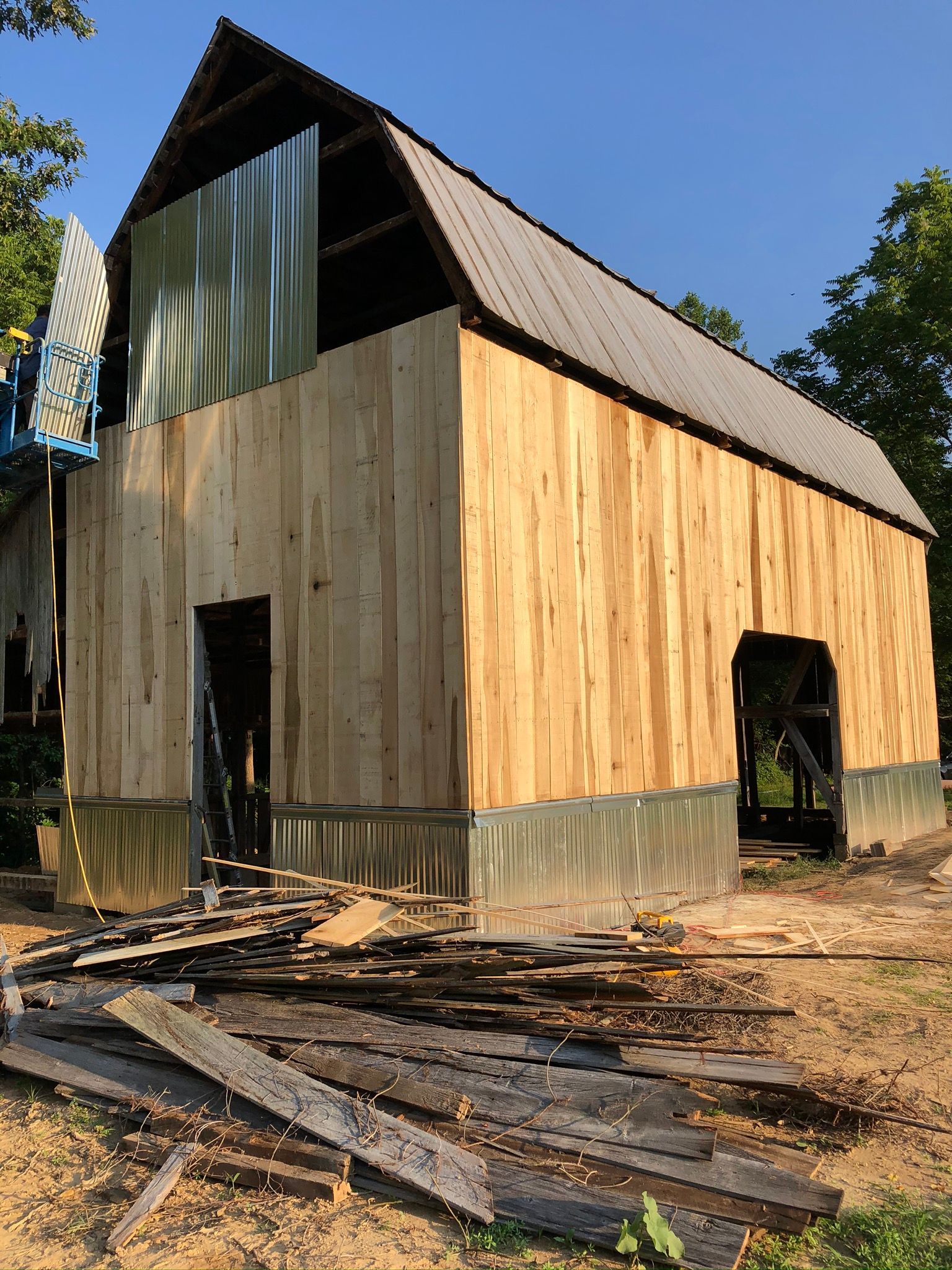 A barn is being remodeled with wooden siding and a metal roof.