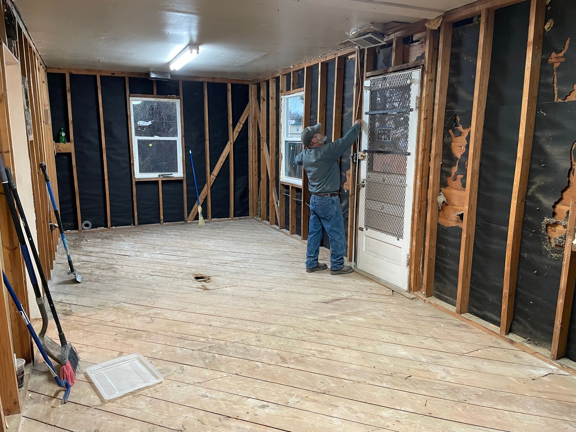 A man is standing in a room with a wooden floor.