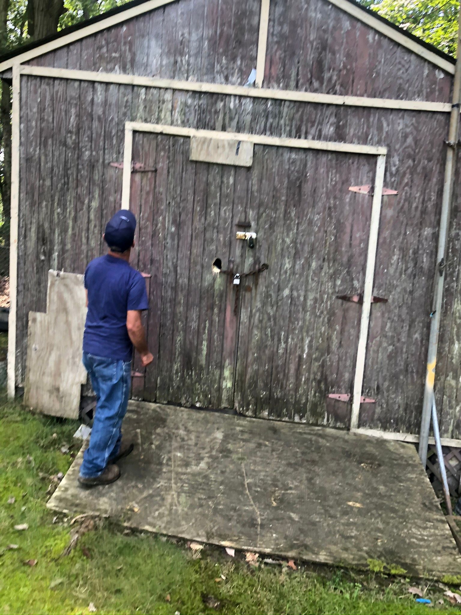 A man is standing in front of a wooden shed.