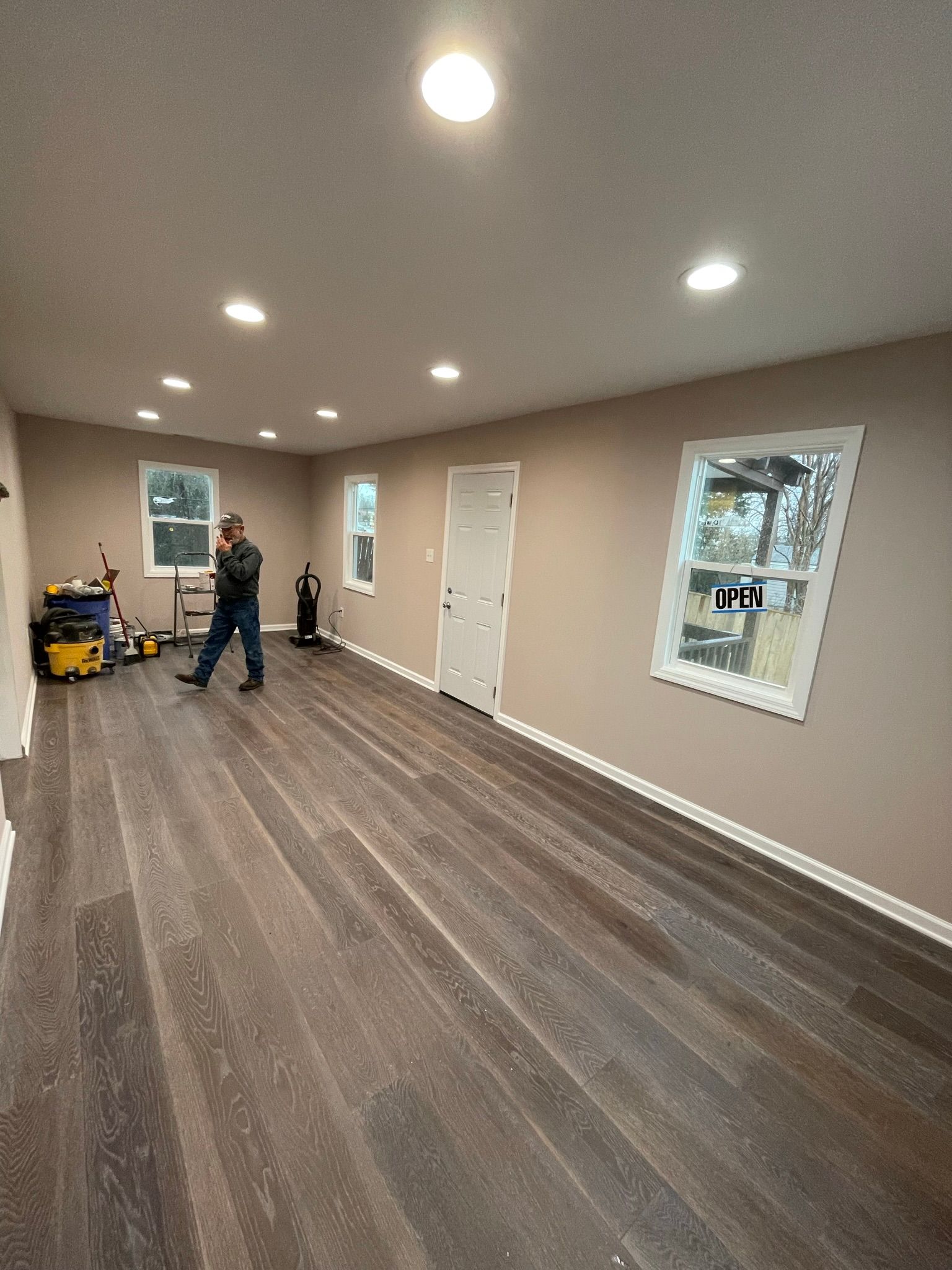 A man is standing in an empty room with hardwood floors.