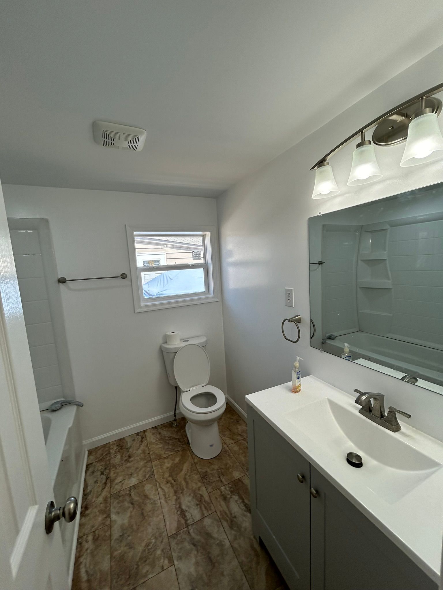 A bathroom with a toilet , sink , and mirror.