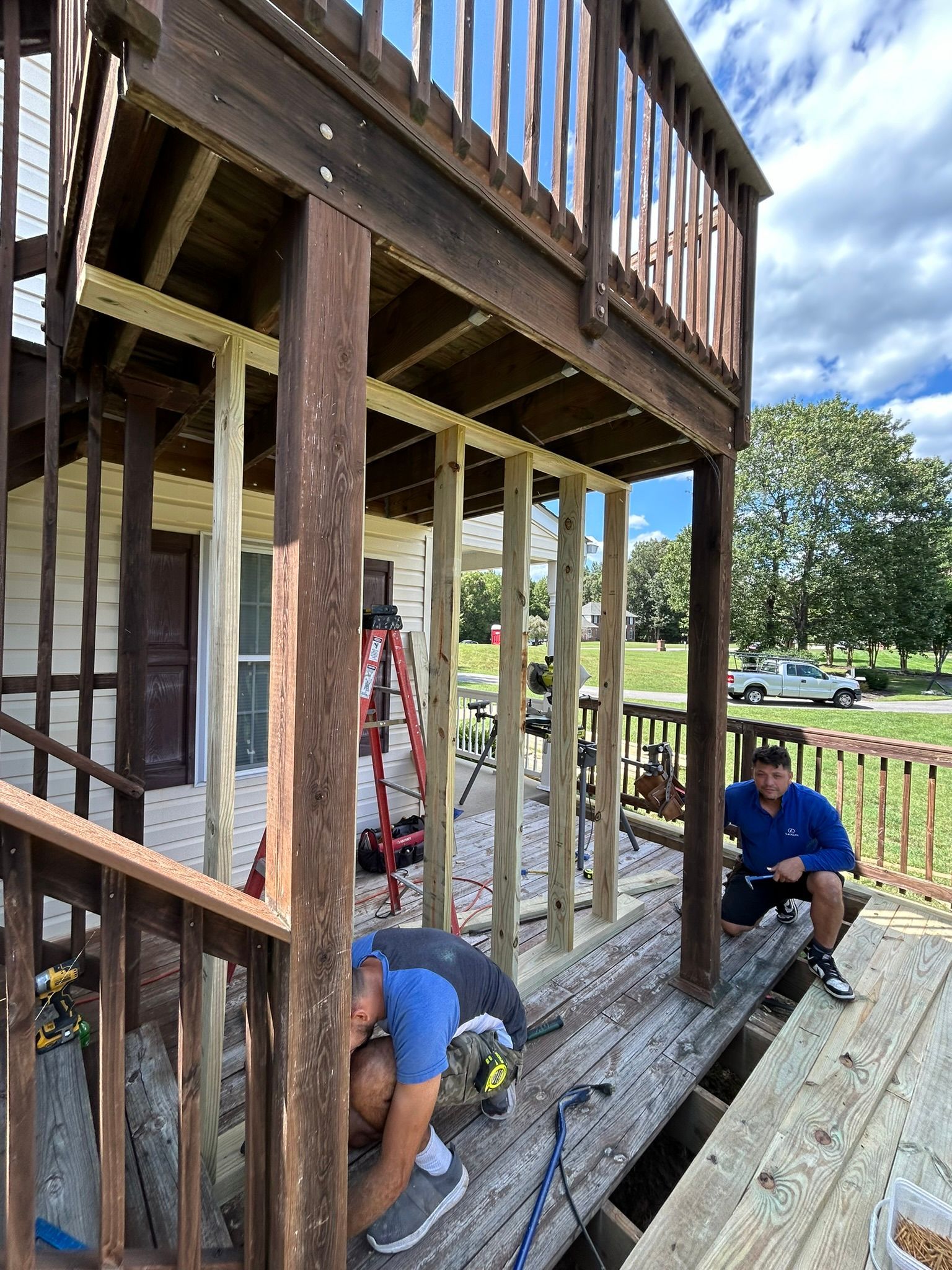A couple of men are working on a wooden deck.