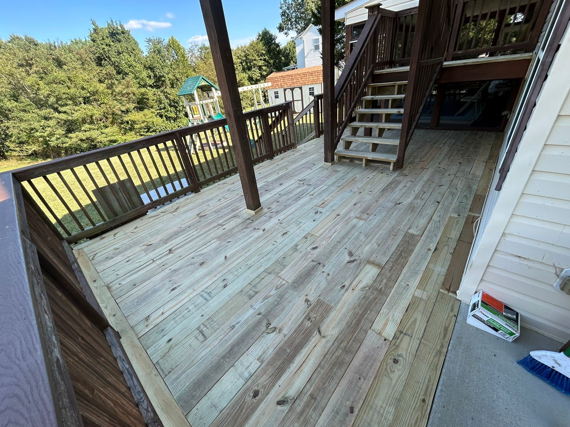 A wooden deck with stairs leading up to the second floor of a house.