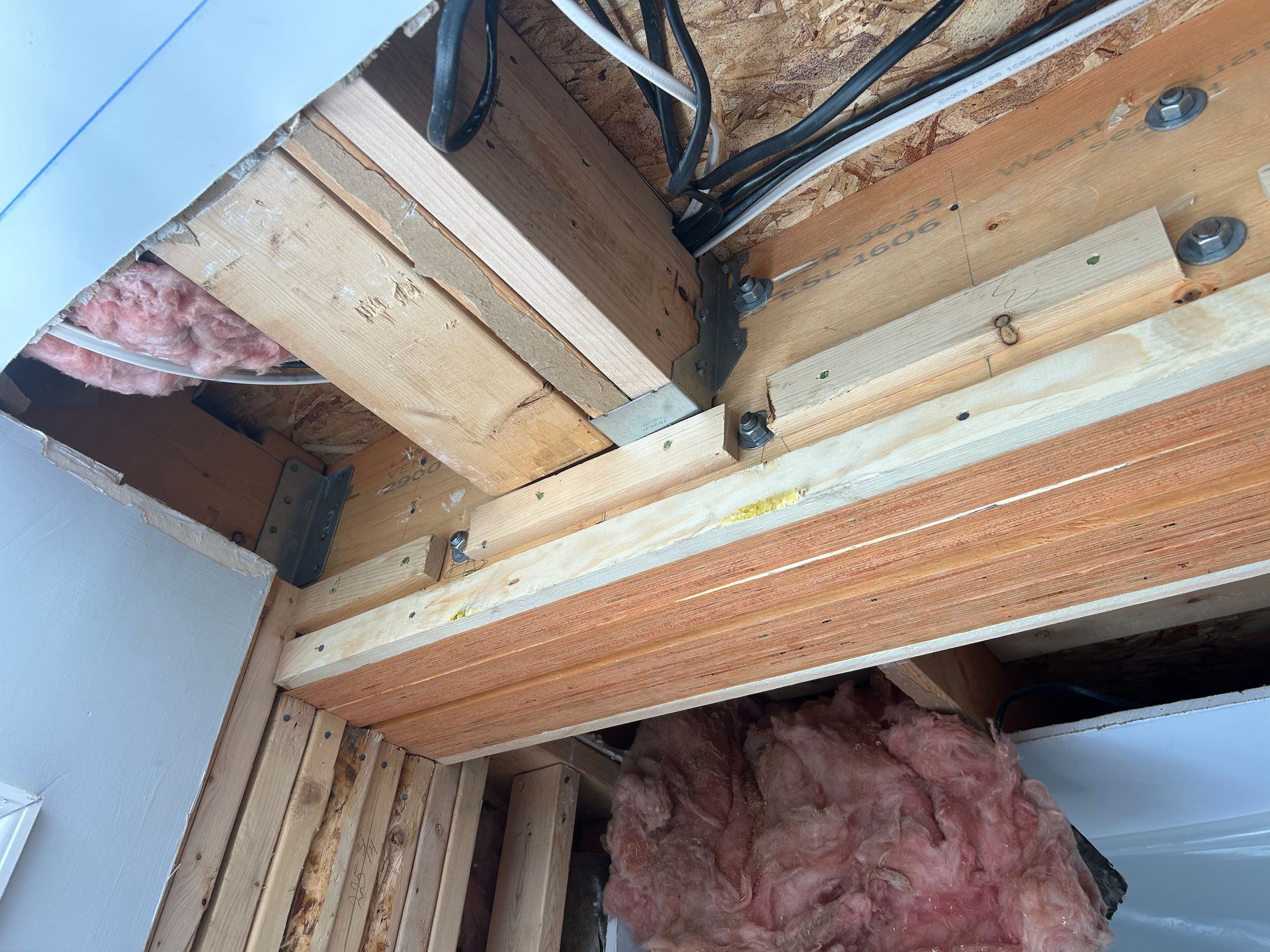 A wooden structure with insulation and wires coming out of it.