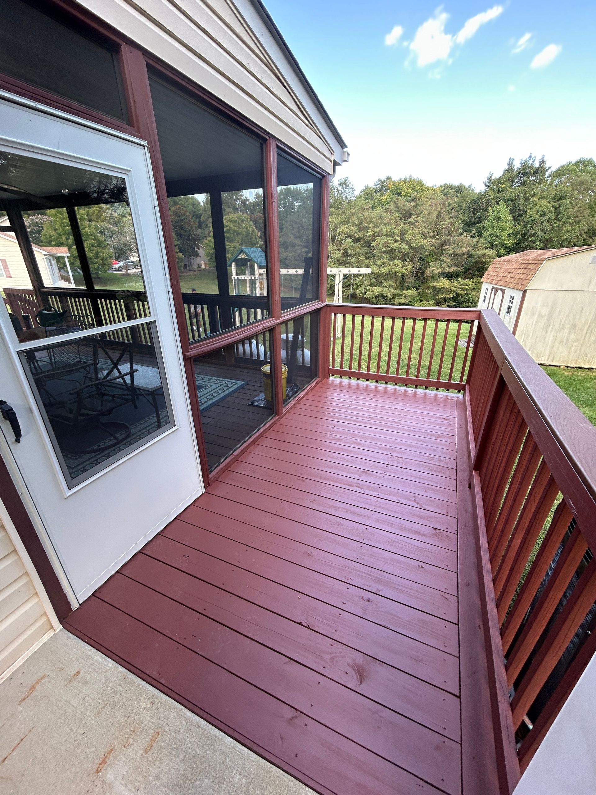 A screened in porch with a red deck and a white door.