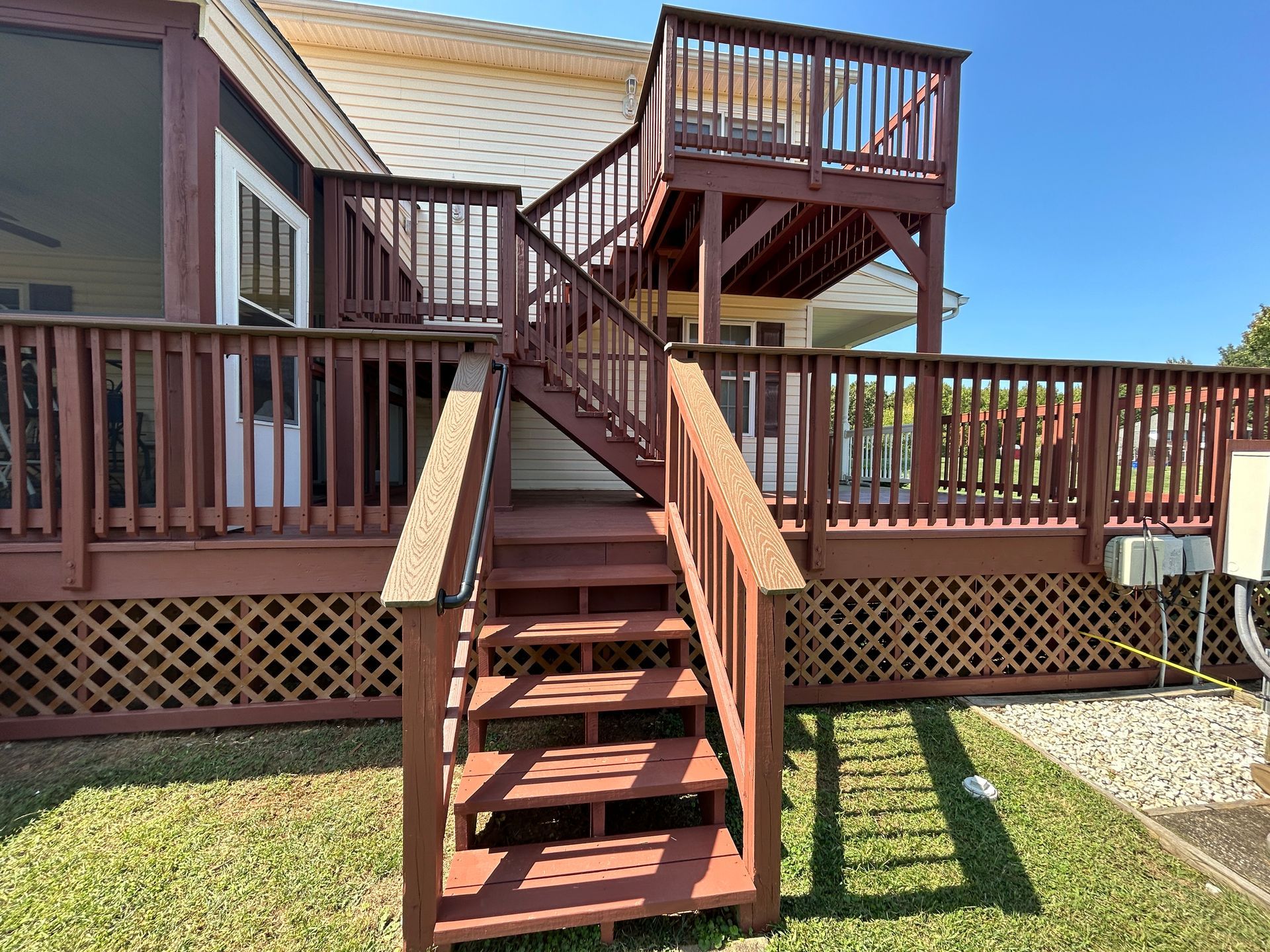 A wooden deck with stairs leading up to it and a screened in porch.