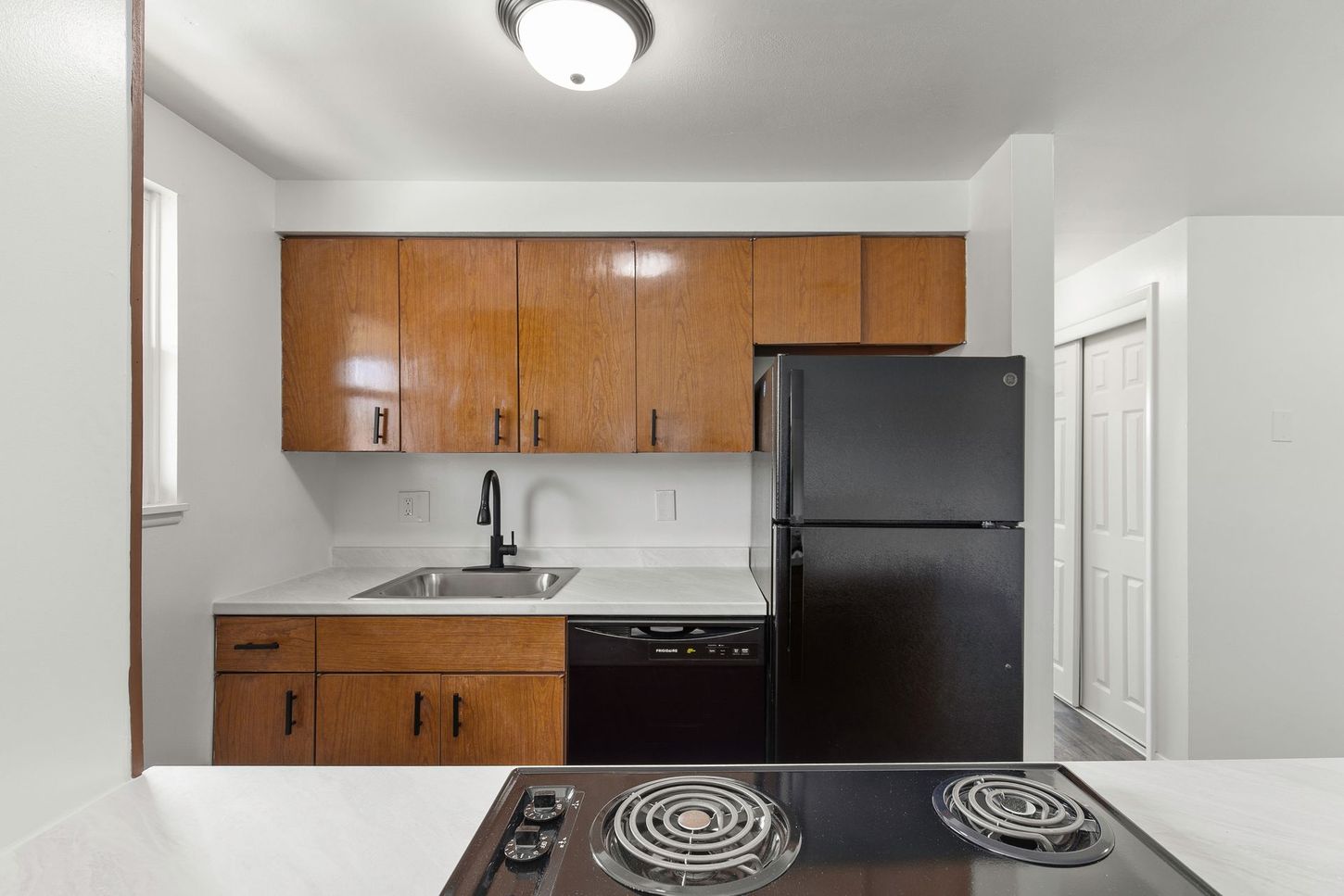 Kitchen with brown cabinets, black appliances, white countertops, and an electric stove.