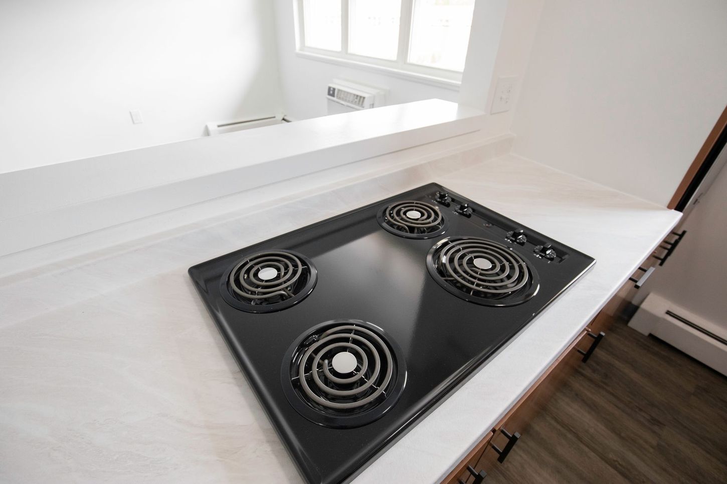 Black electric cooktop on a white countertop in a kitchen.