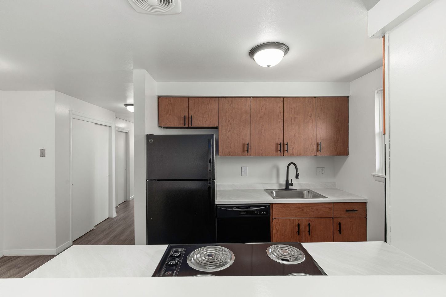 Kitchen with brown cabinets, black appliances, and a white countertop and island.