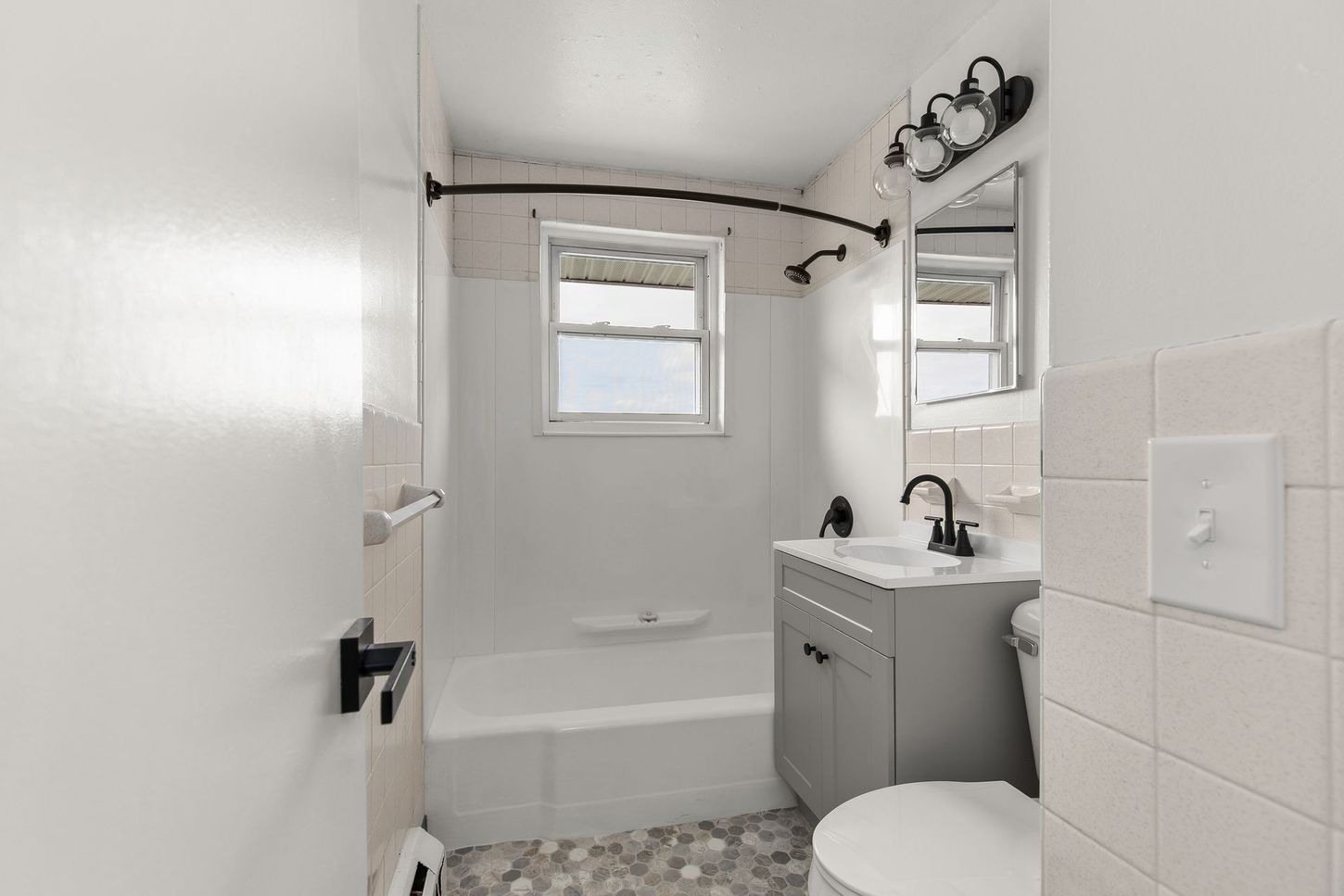 Bathroom with white walls, shower, gray vanity, and toilet.