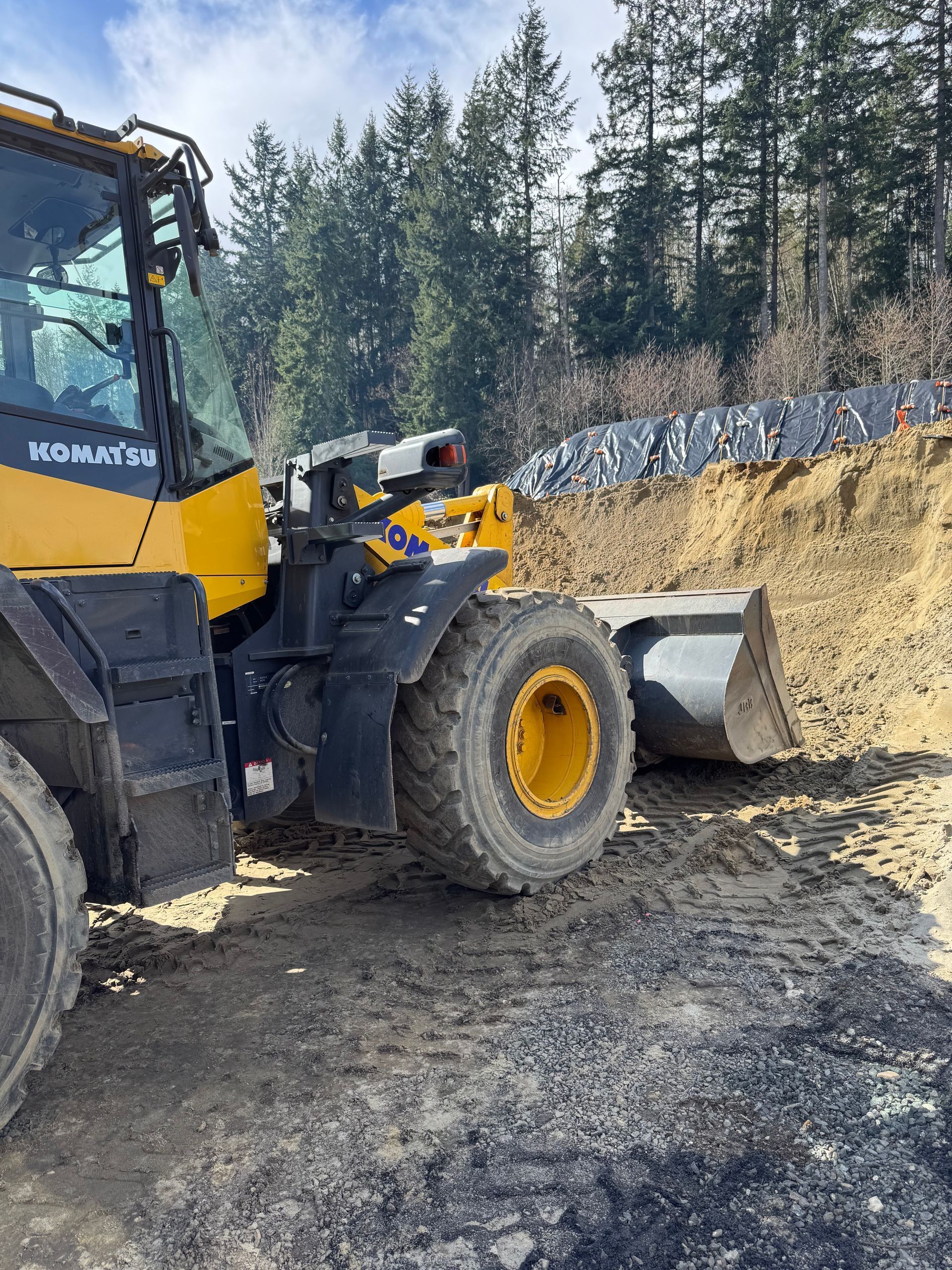 Yellow Komatsu loader scoops up dirt on a construction site.