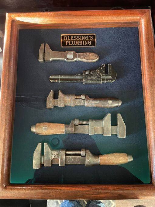 Shadow box displaying five vintage pipe wrenches with 