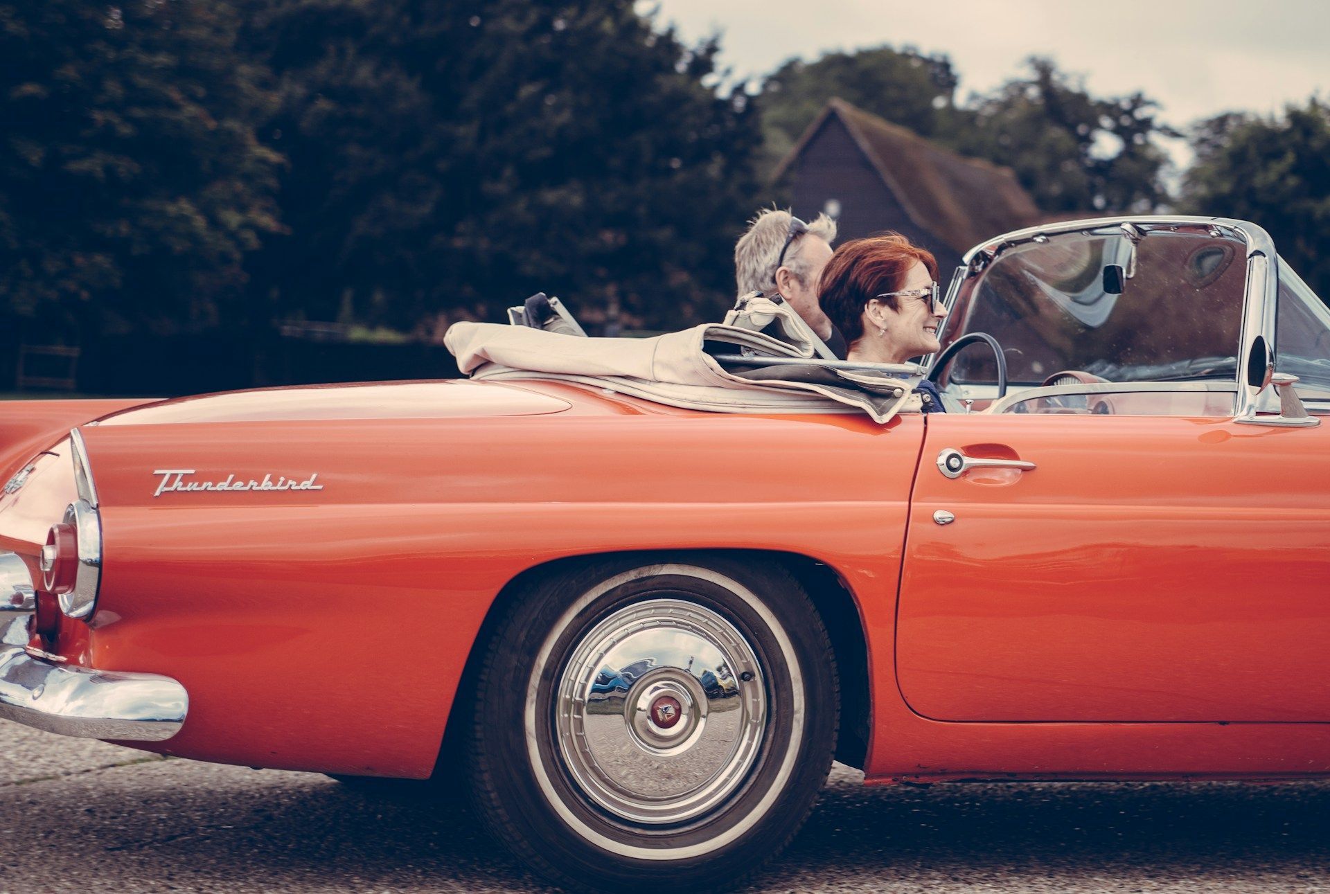 A man and woman are sitting in a red convertible car.