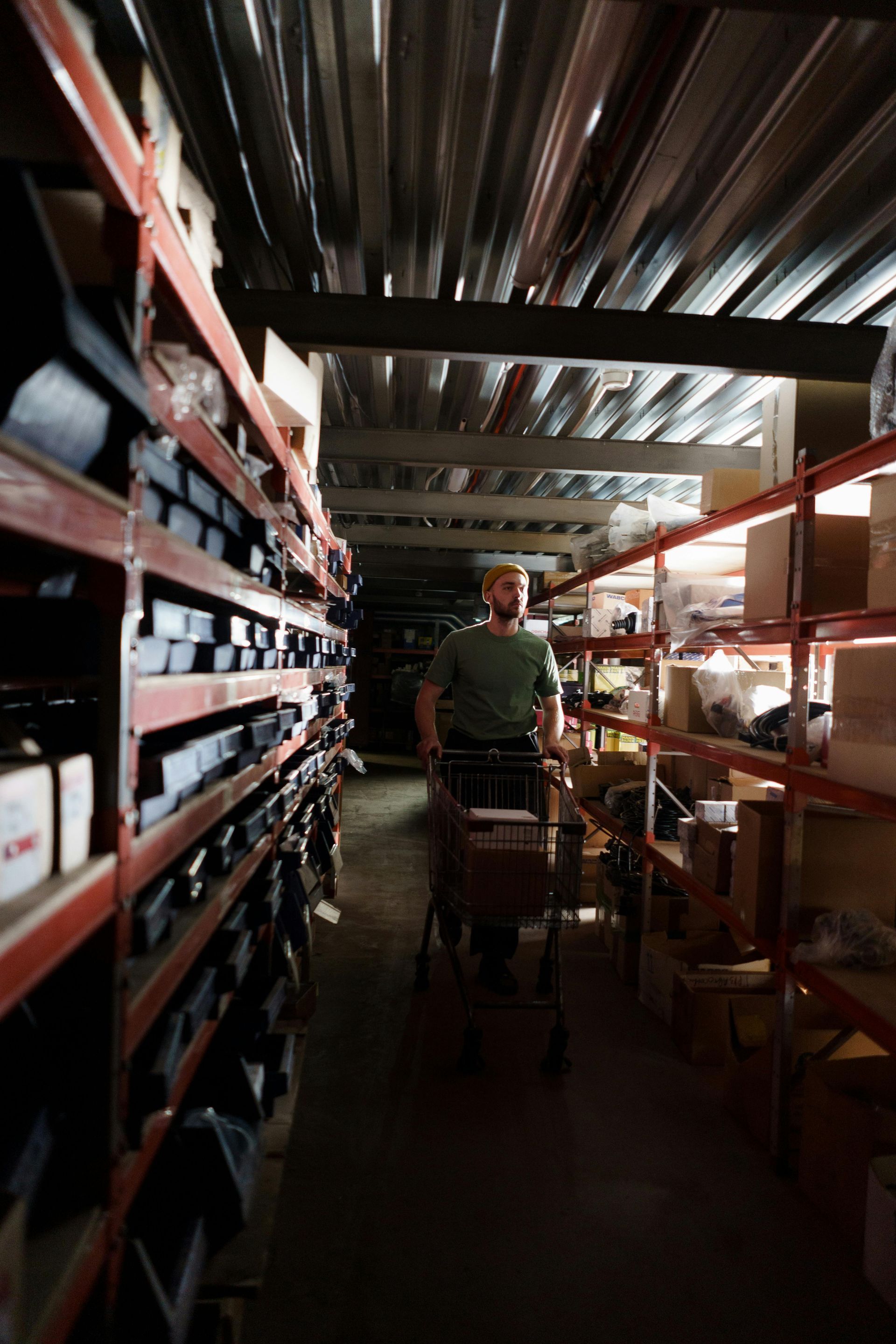 A man in a wheelchair is pushing a cart in a warehouse.