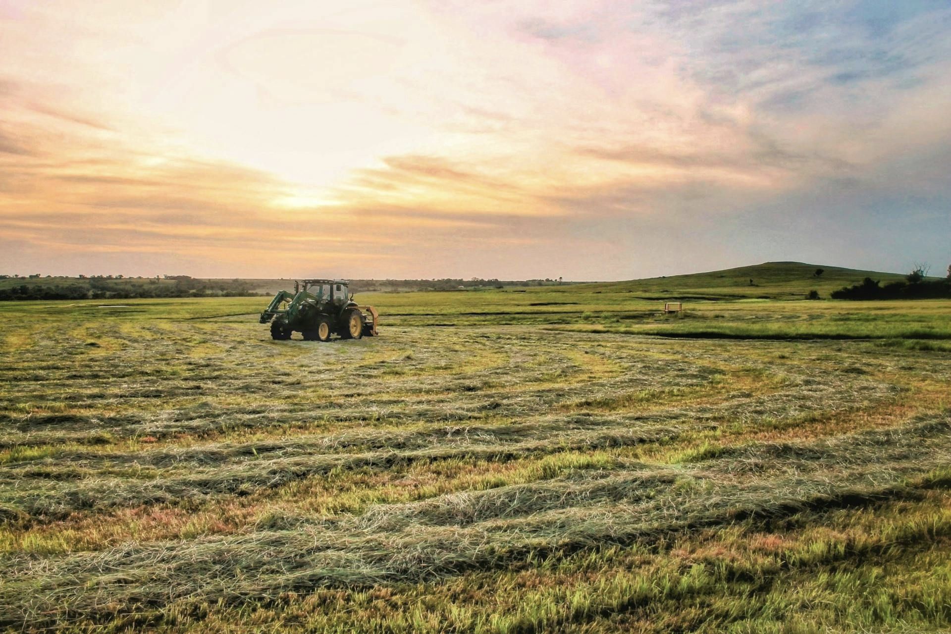 A tractor is working in a field at sunset.