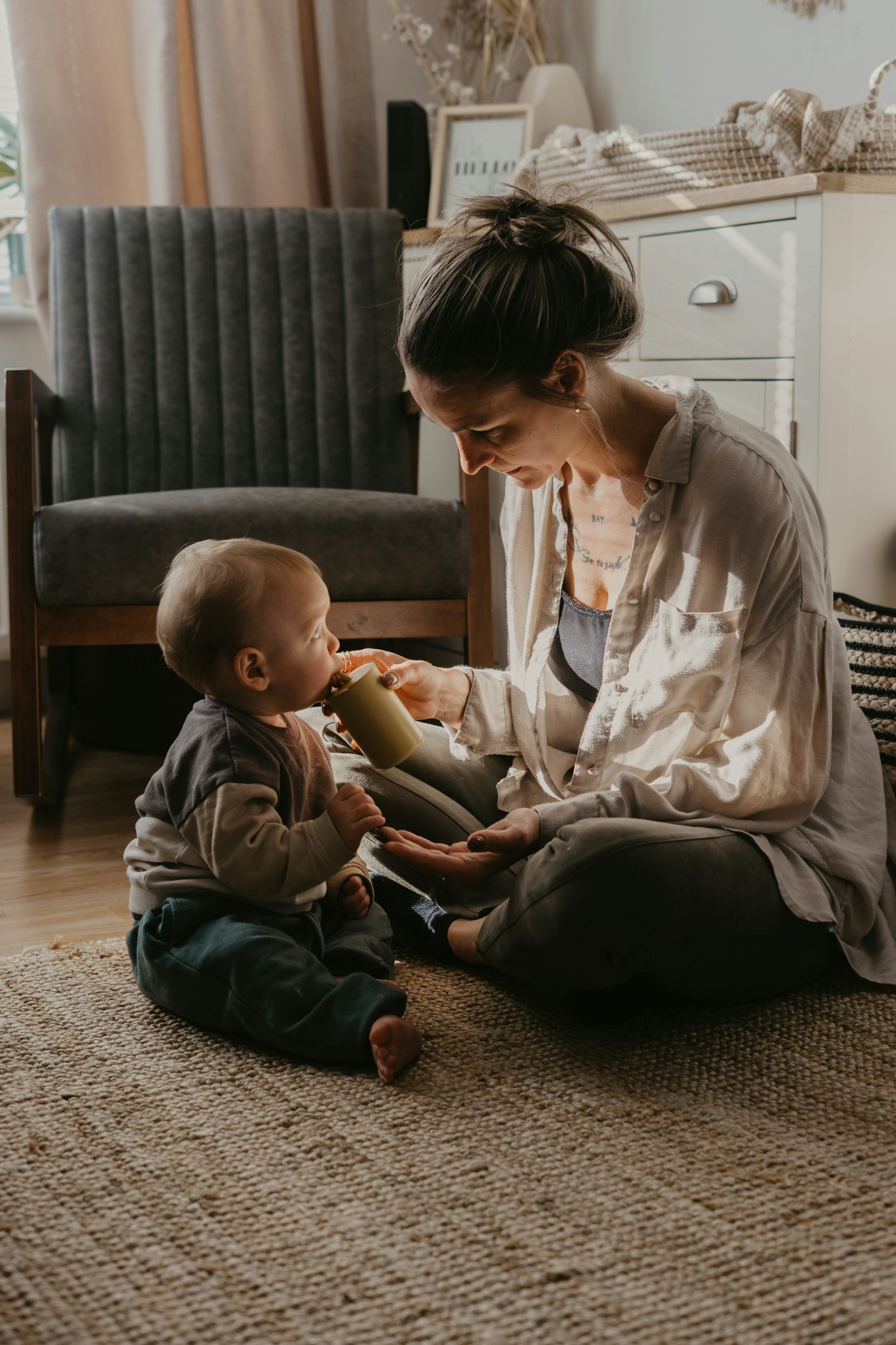 A woman is sitting on the floor playing with a baby.