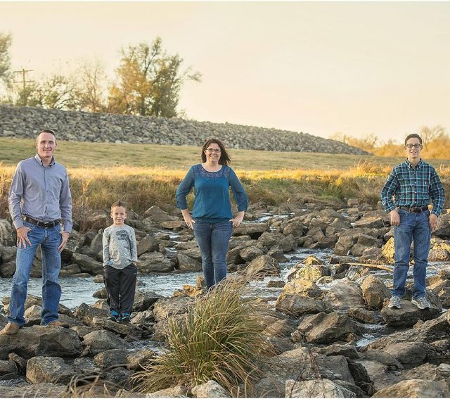 A family is posing for a picture while sitting on a log.