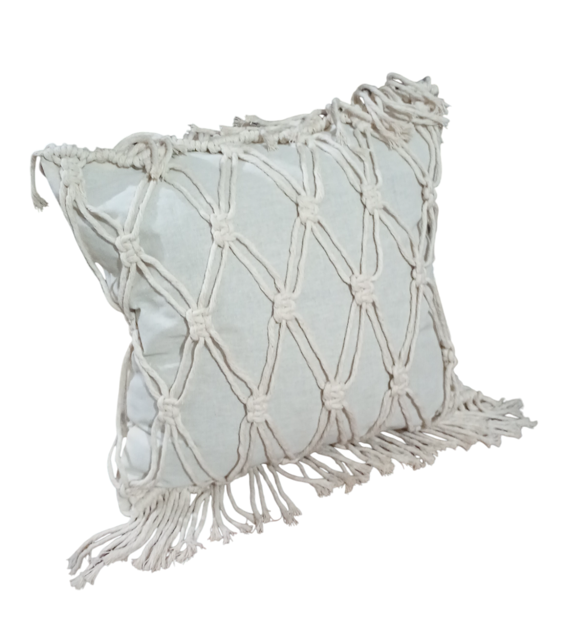 Una almohada de macramé blanca con flecos sobre un fondo blanco.
