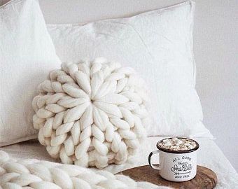 Primer plano de una almohada gigante de punto, redonda y de color topo.