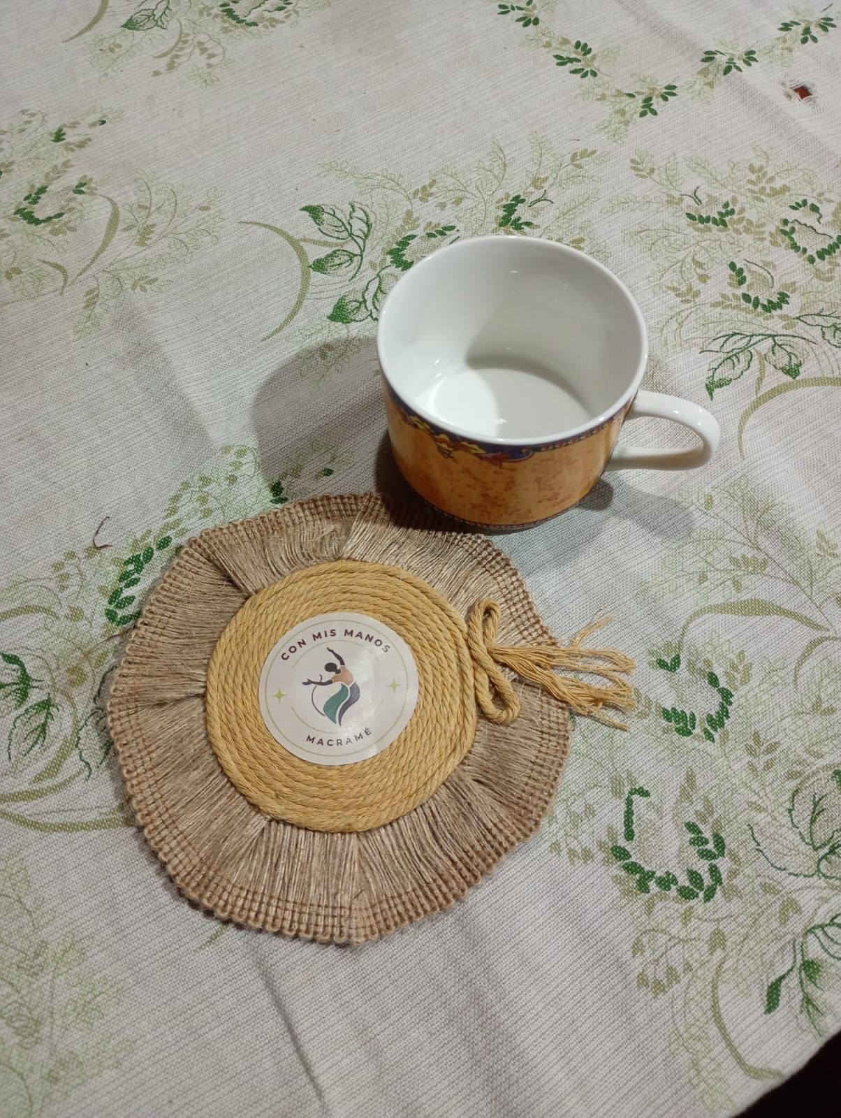 Mantel individual redondo de yute tejido con un disco central beige.