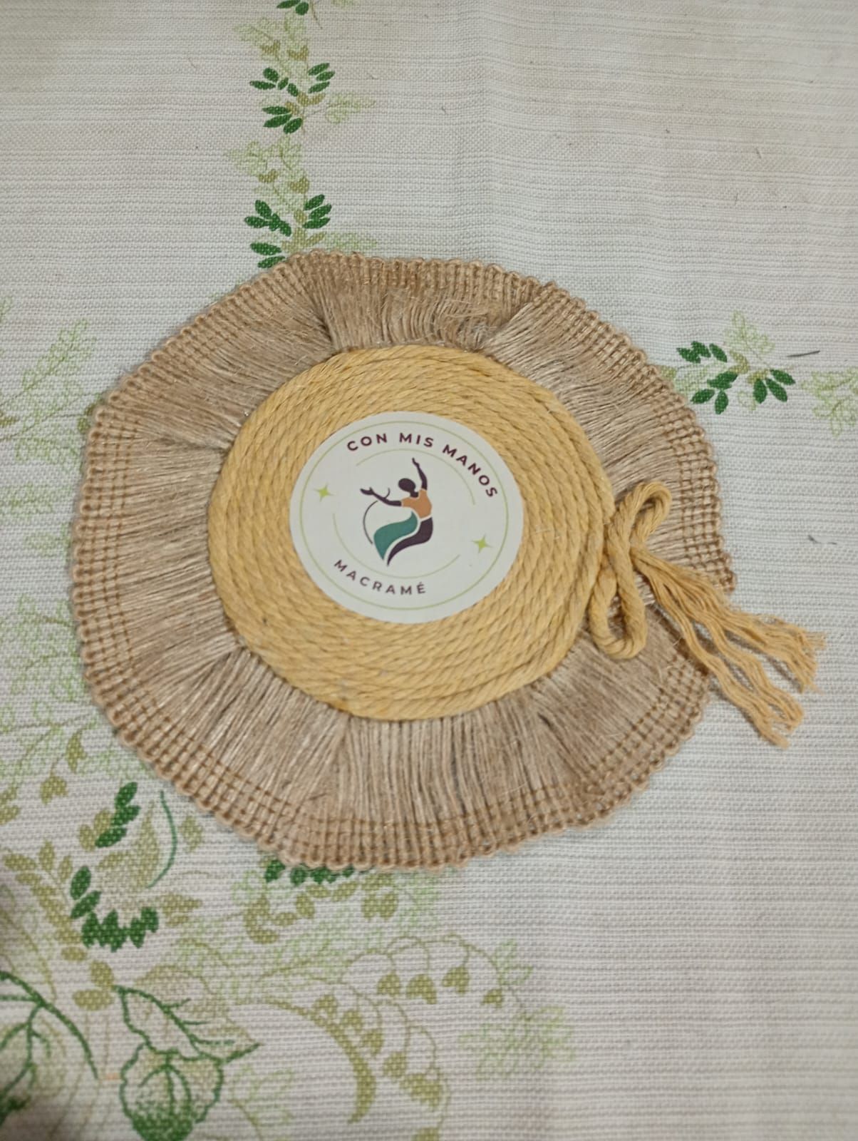 Mantel individual redondo de yute tejido con un disco central beige.