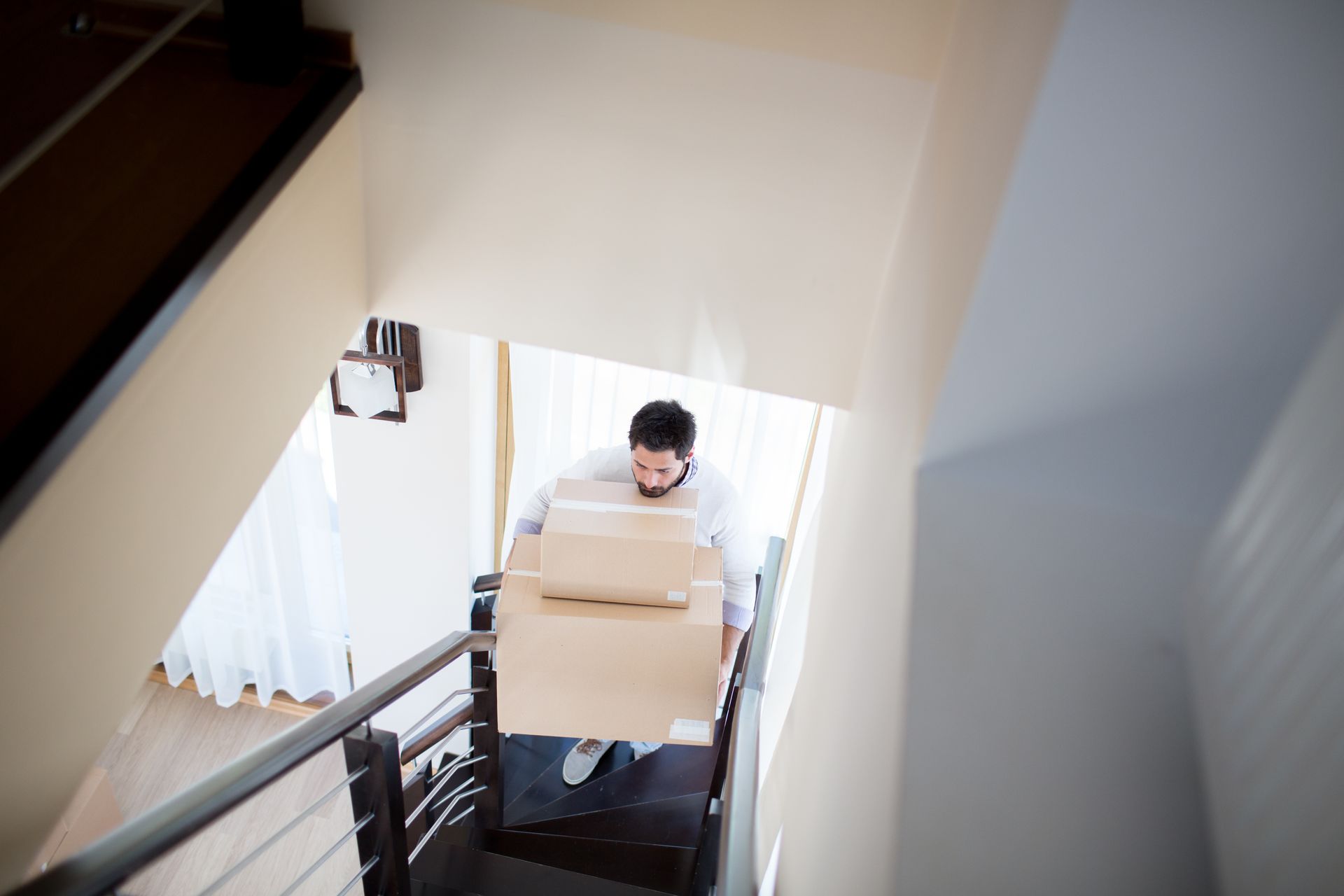 A man is carrying a cardboard box up a set of stairs.