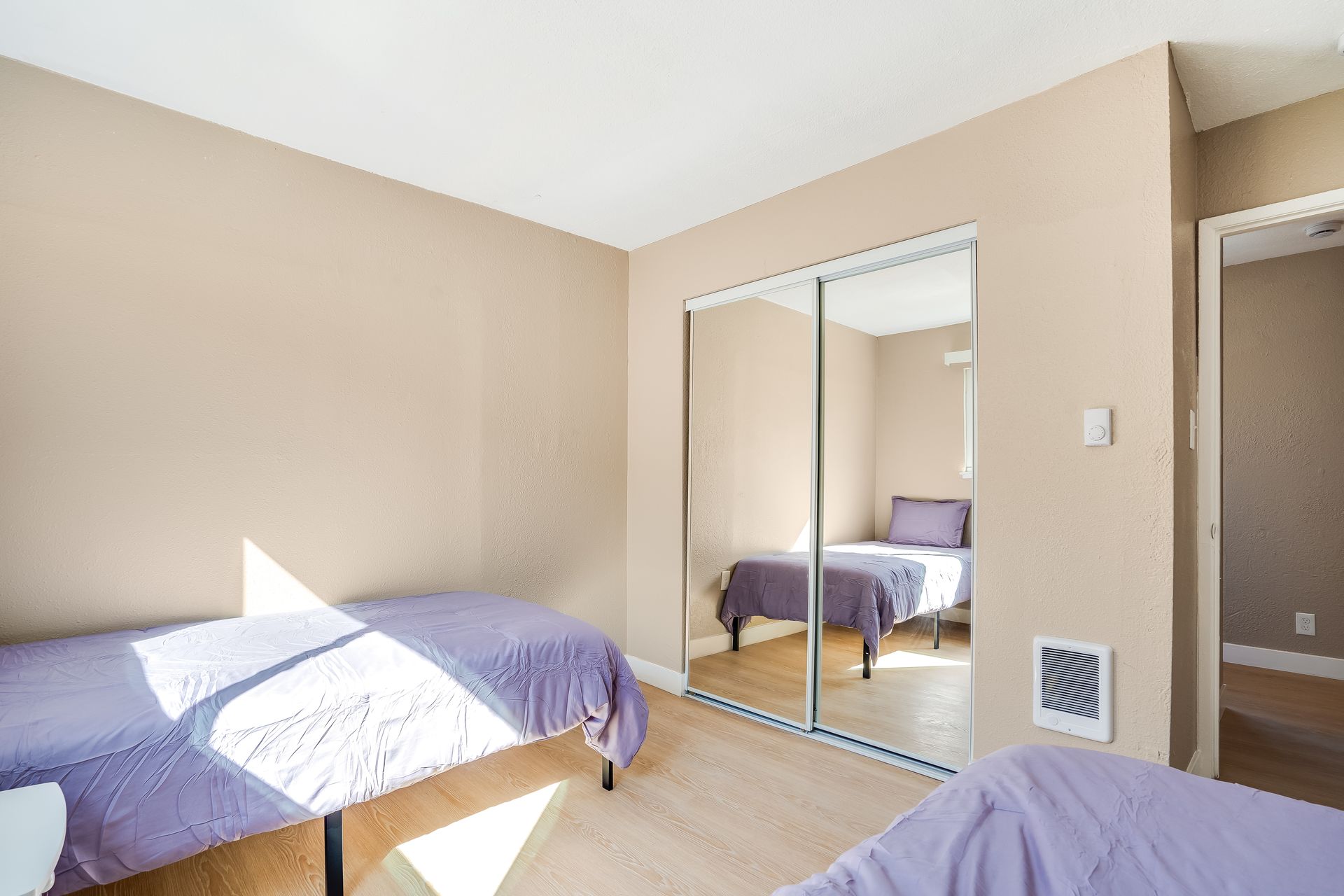 A bedroom with two beds and a sliding glass door.