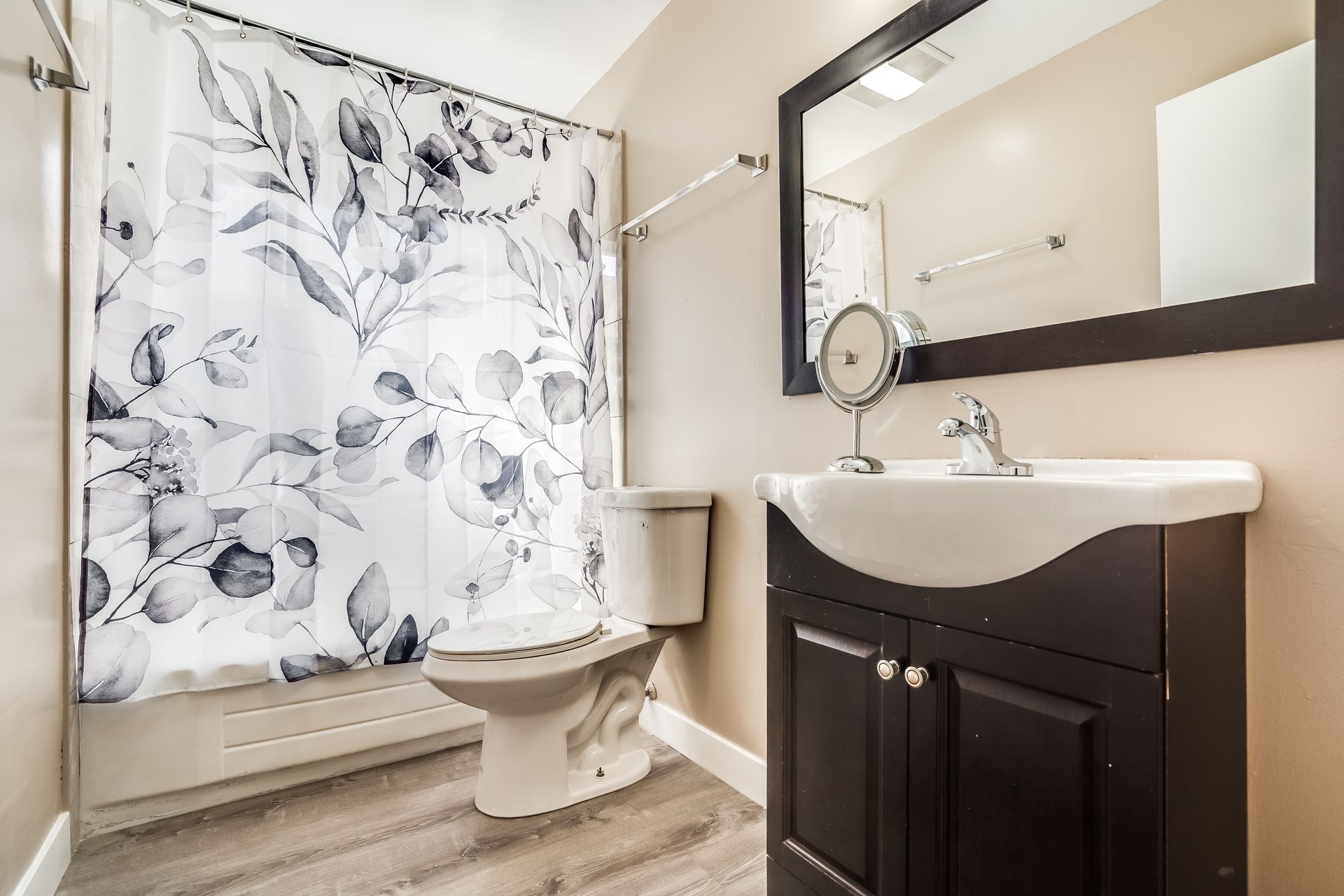 A bathroom with a toilet , sink , mirror and shower curtain.