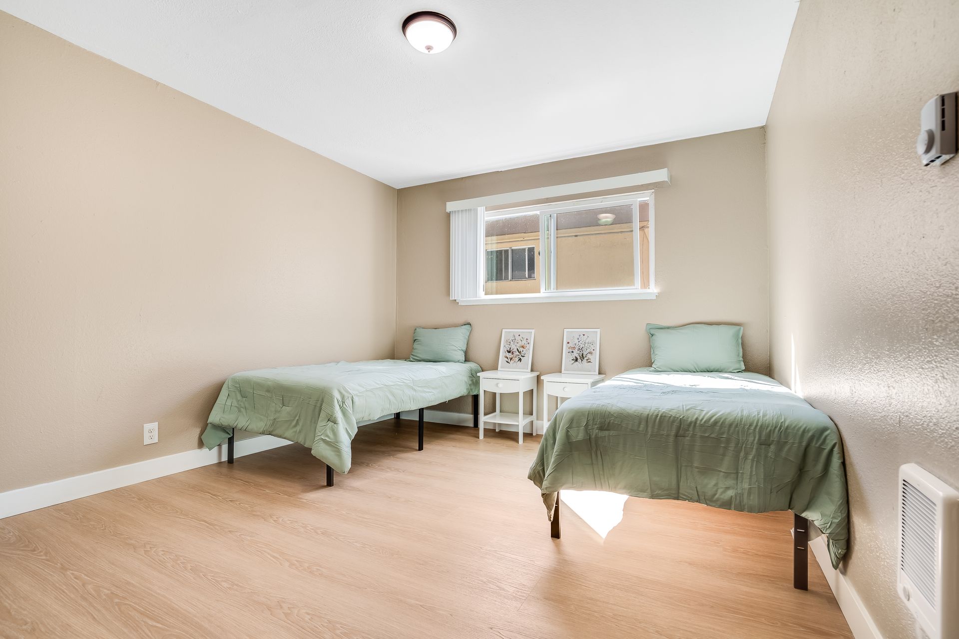 A bedroom with two beds and a window.