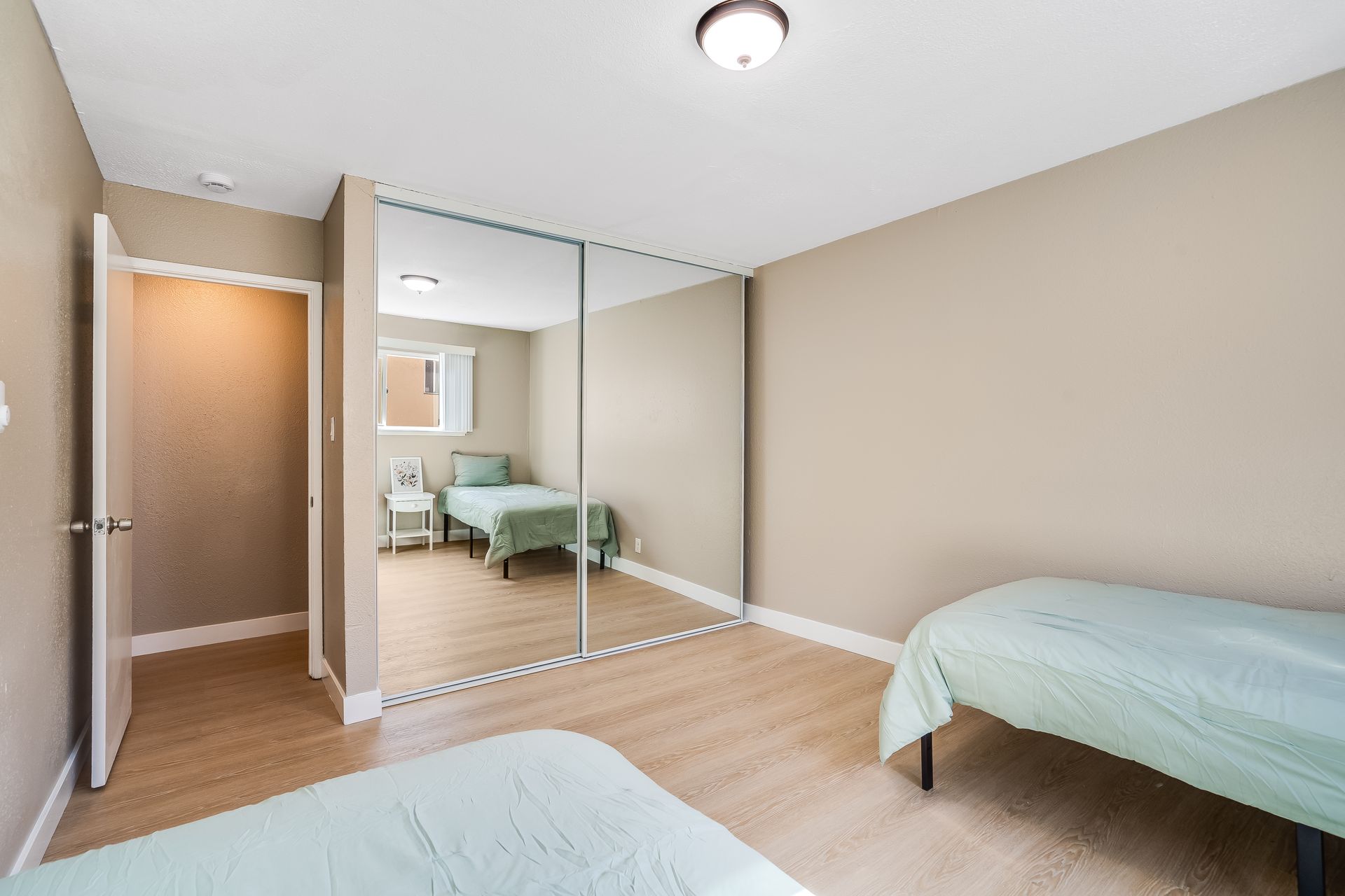 A bedroom with two beds and a large mirrored wardrobe.
