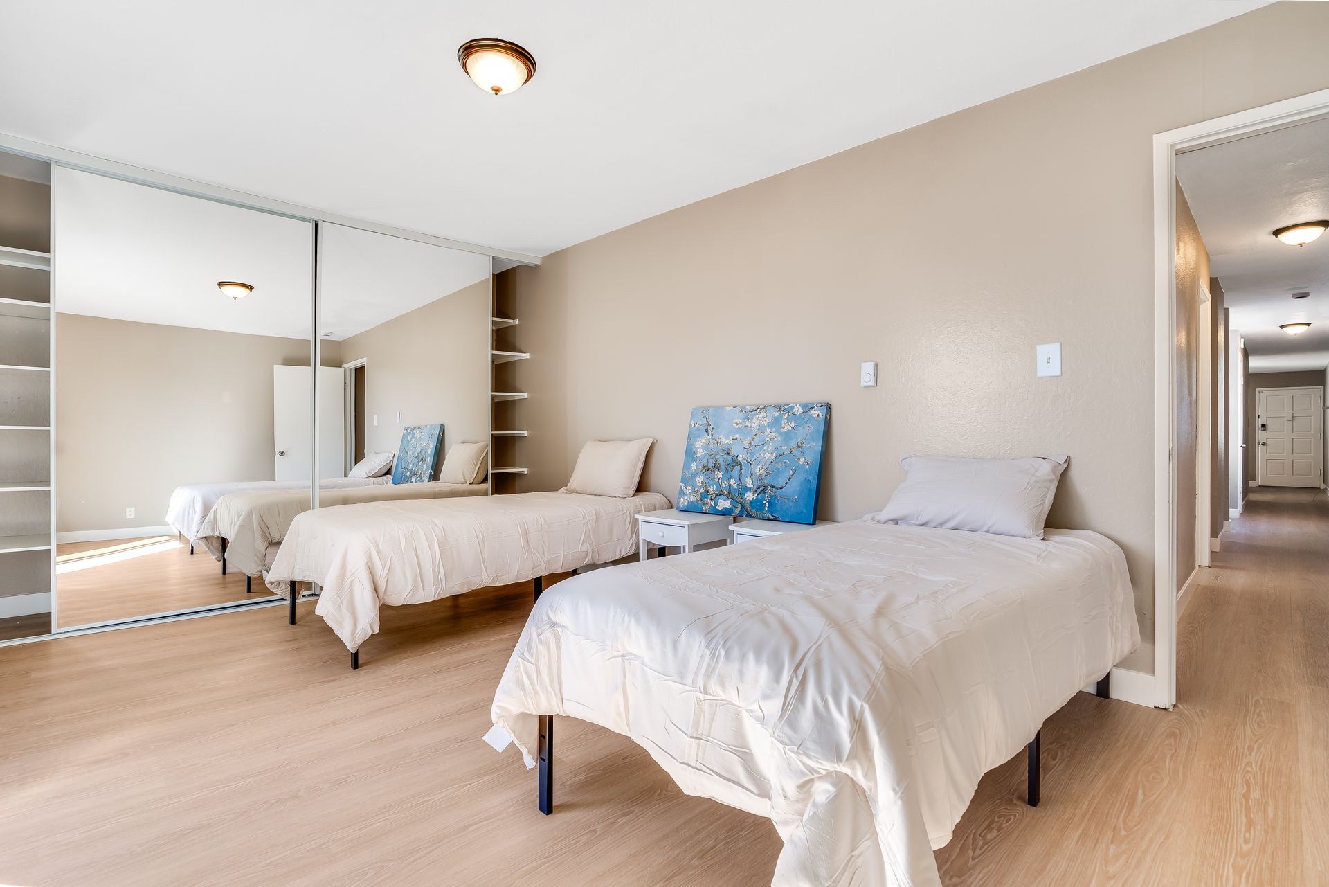 A bedroom with two beds and a mirrored closet.