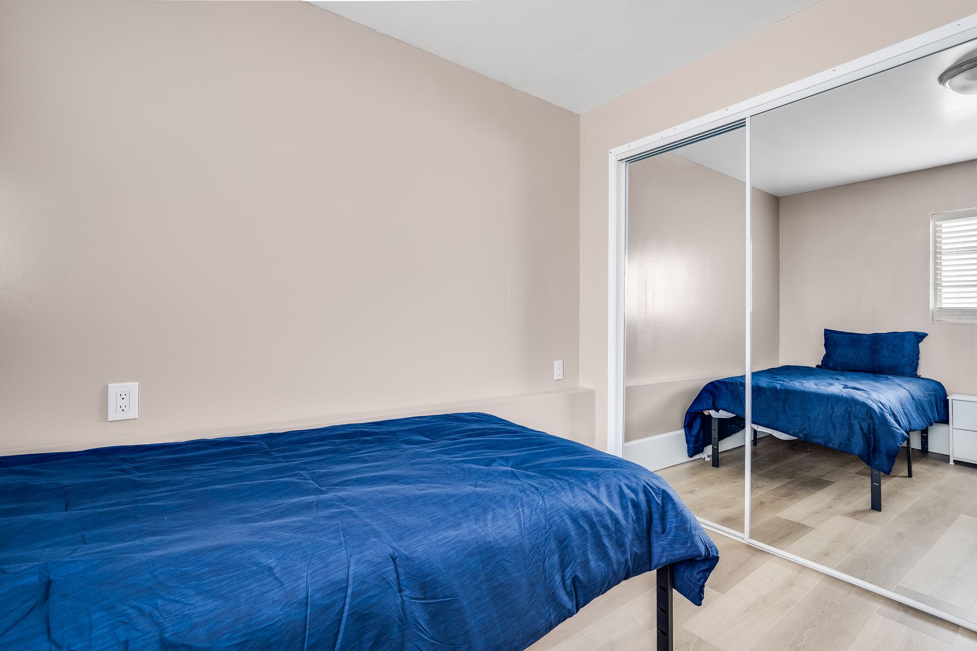 A bedroom with a bed and a mirrored closet.
