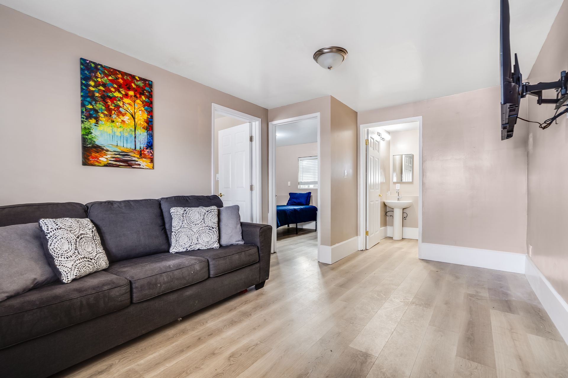 A living room with a couch , television and a painting on the wall.