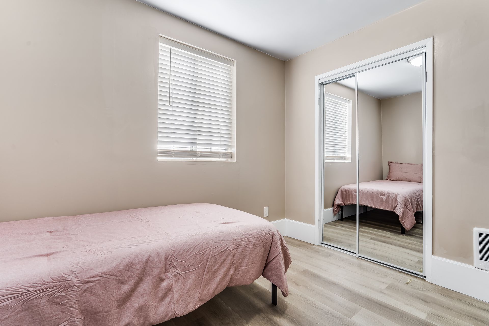 A bedroom with a bed and a mirrored closet.