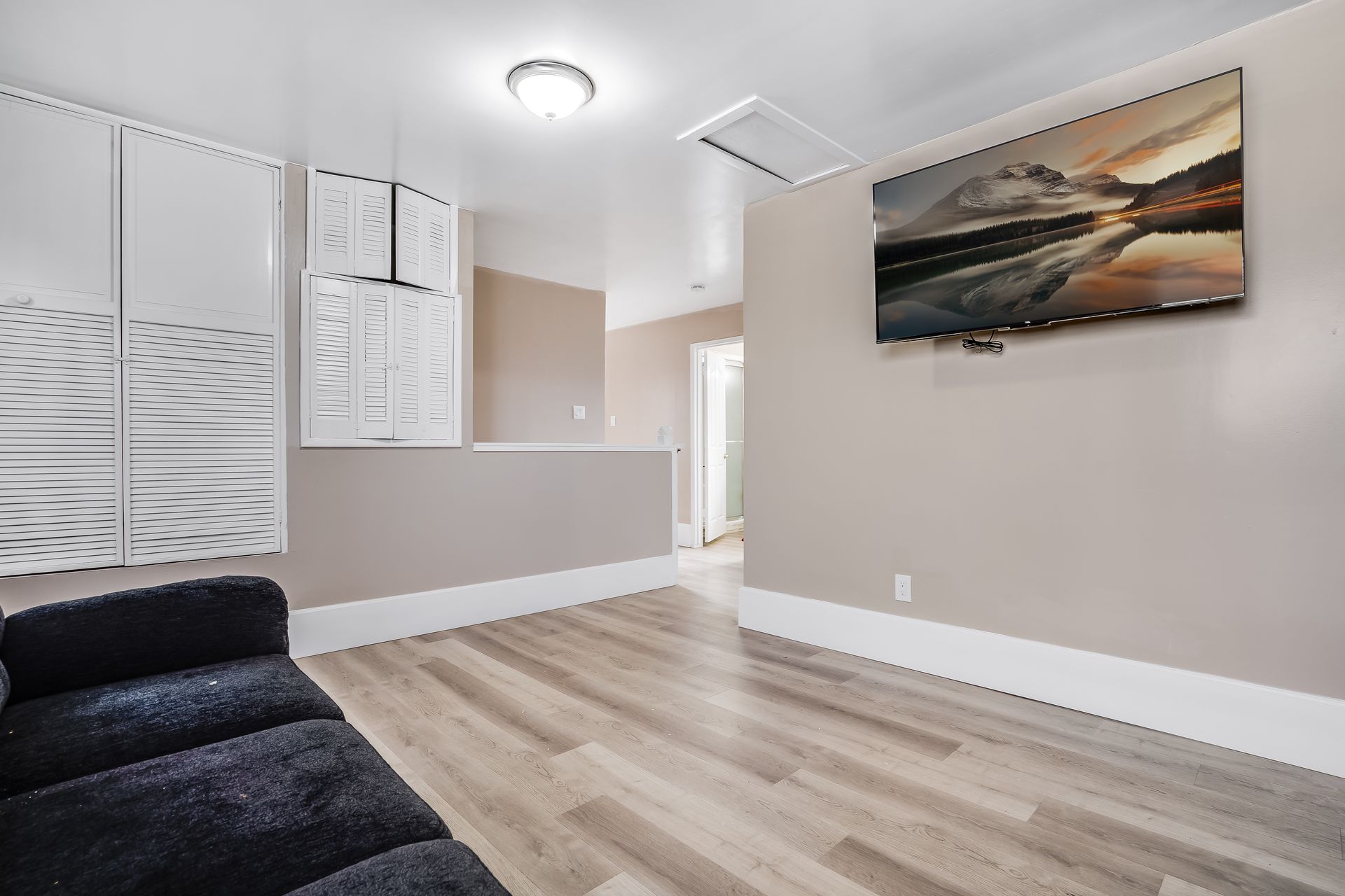 A living room with a couch and a flat screen tv on the wall.