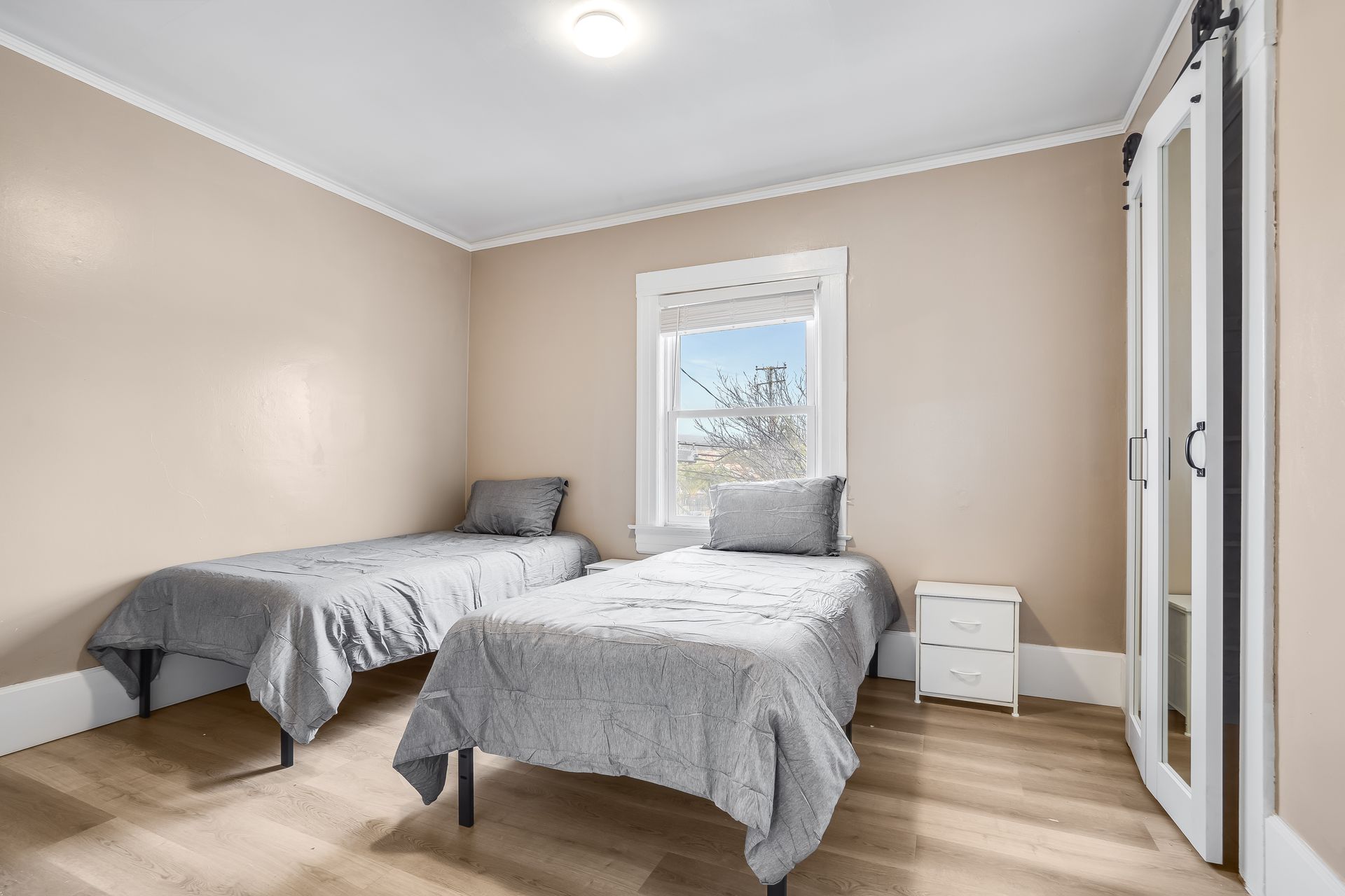 A bedroom with two twin beds and a window.