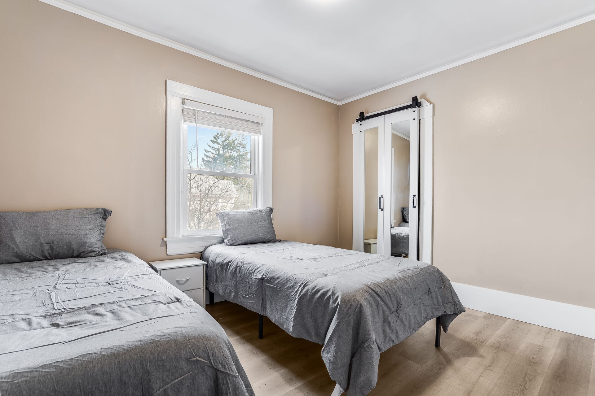 A bedroom with two beds , a window and a sliding barn door.
