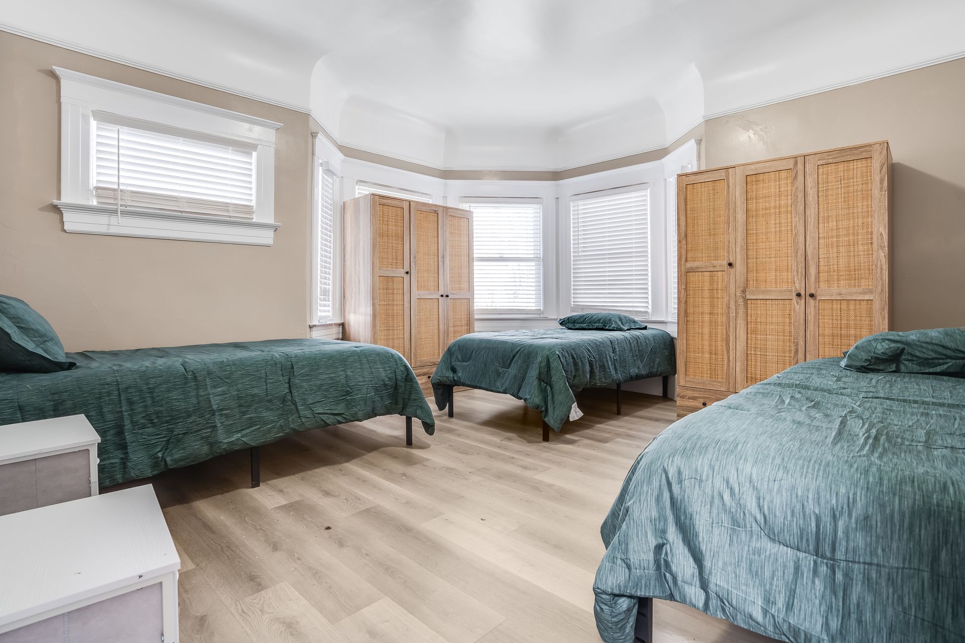 A bedroom with three beds and a window.