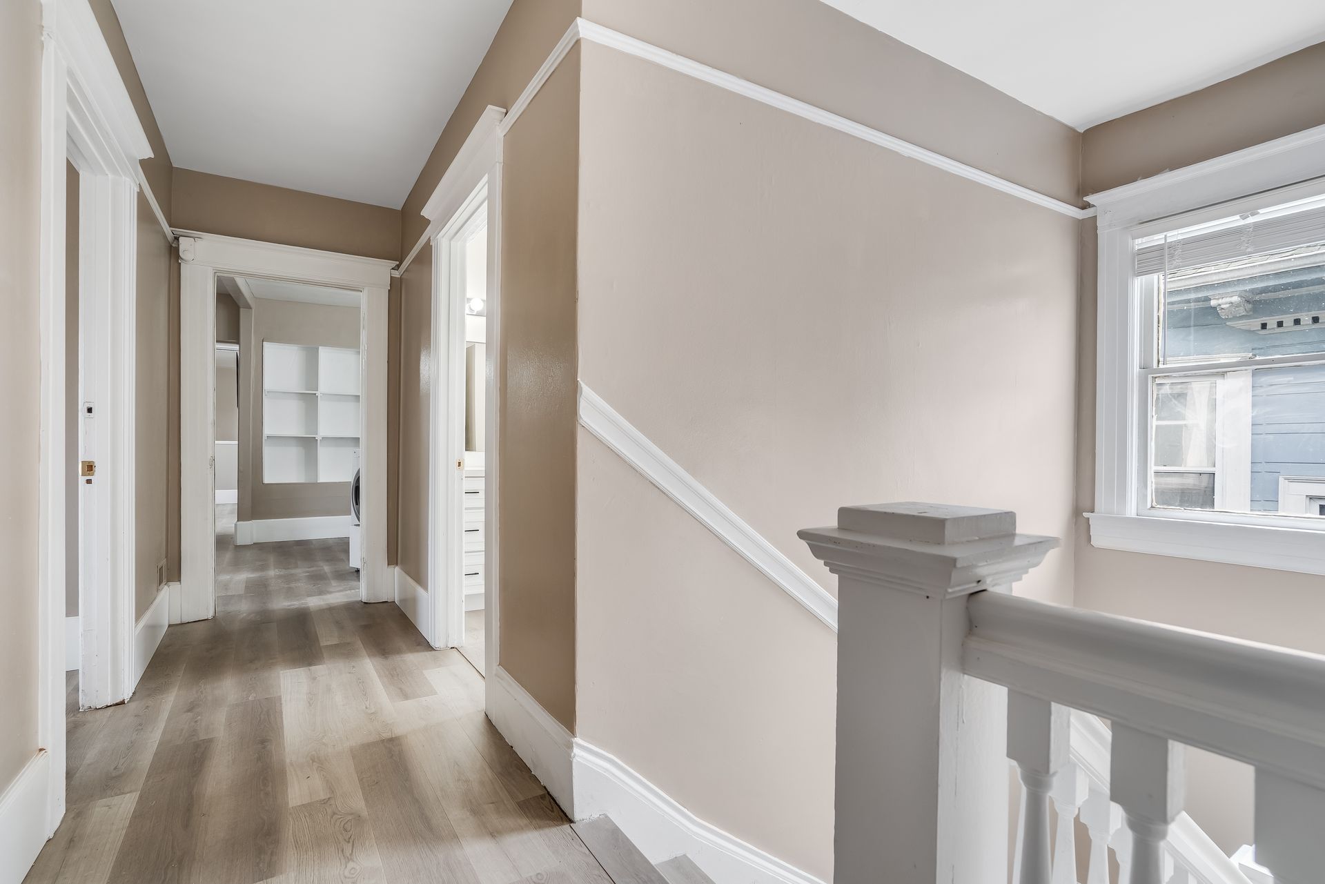 A hallway with a staircase and a window in a house.