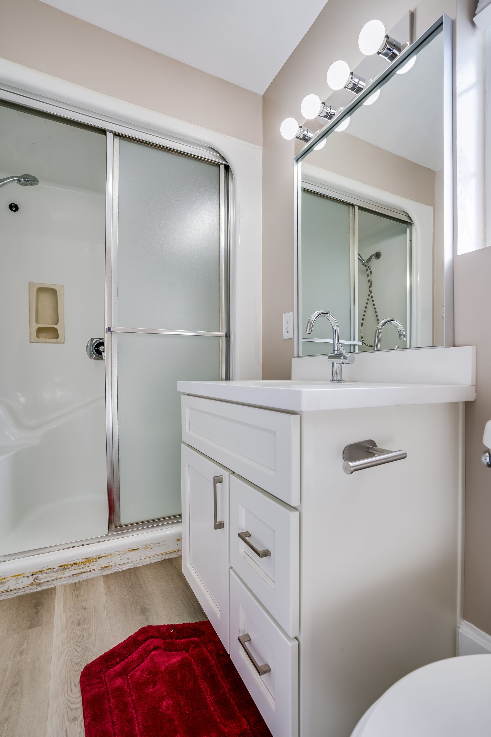 A bathroom with a sink , toilet , shower and mirror.