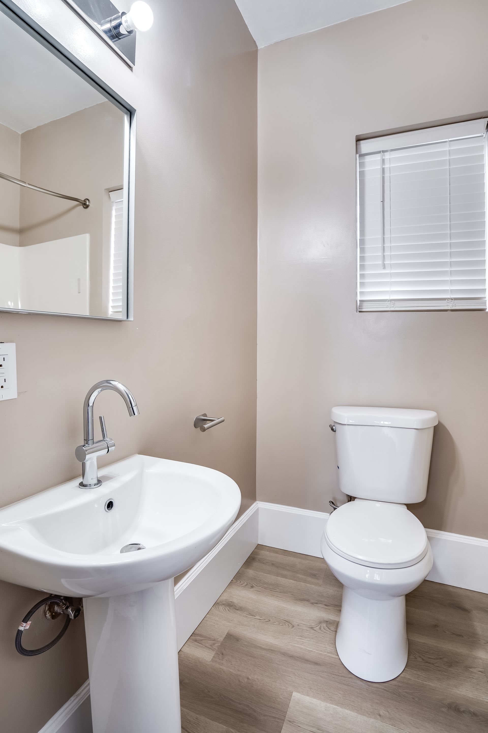 A bathroom with a toilet , sink and mirror.