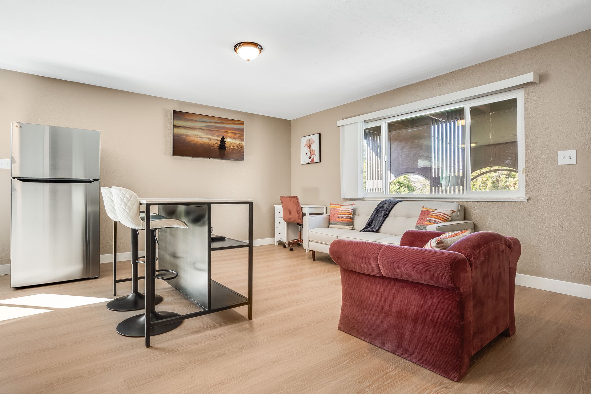 A living room with a couch , chair , table and refrigerator.
