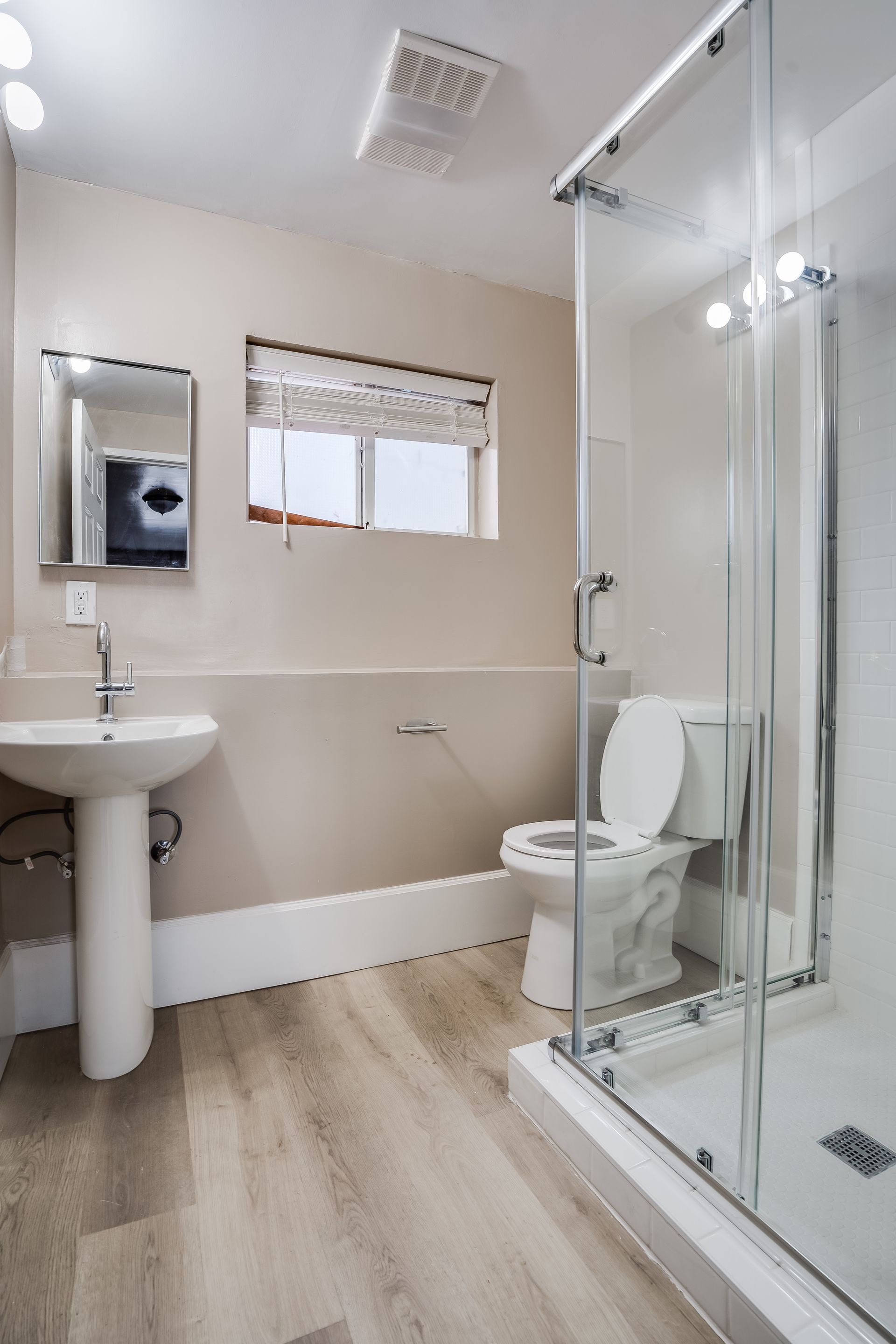A bathroom with a toilet , sink and shower.