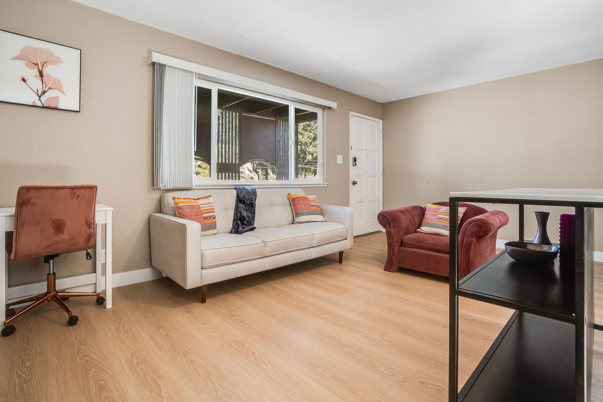 A living room with a couch , chair , desk and shelf.