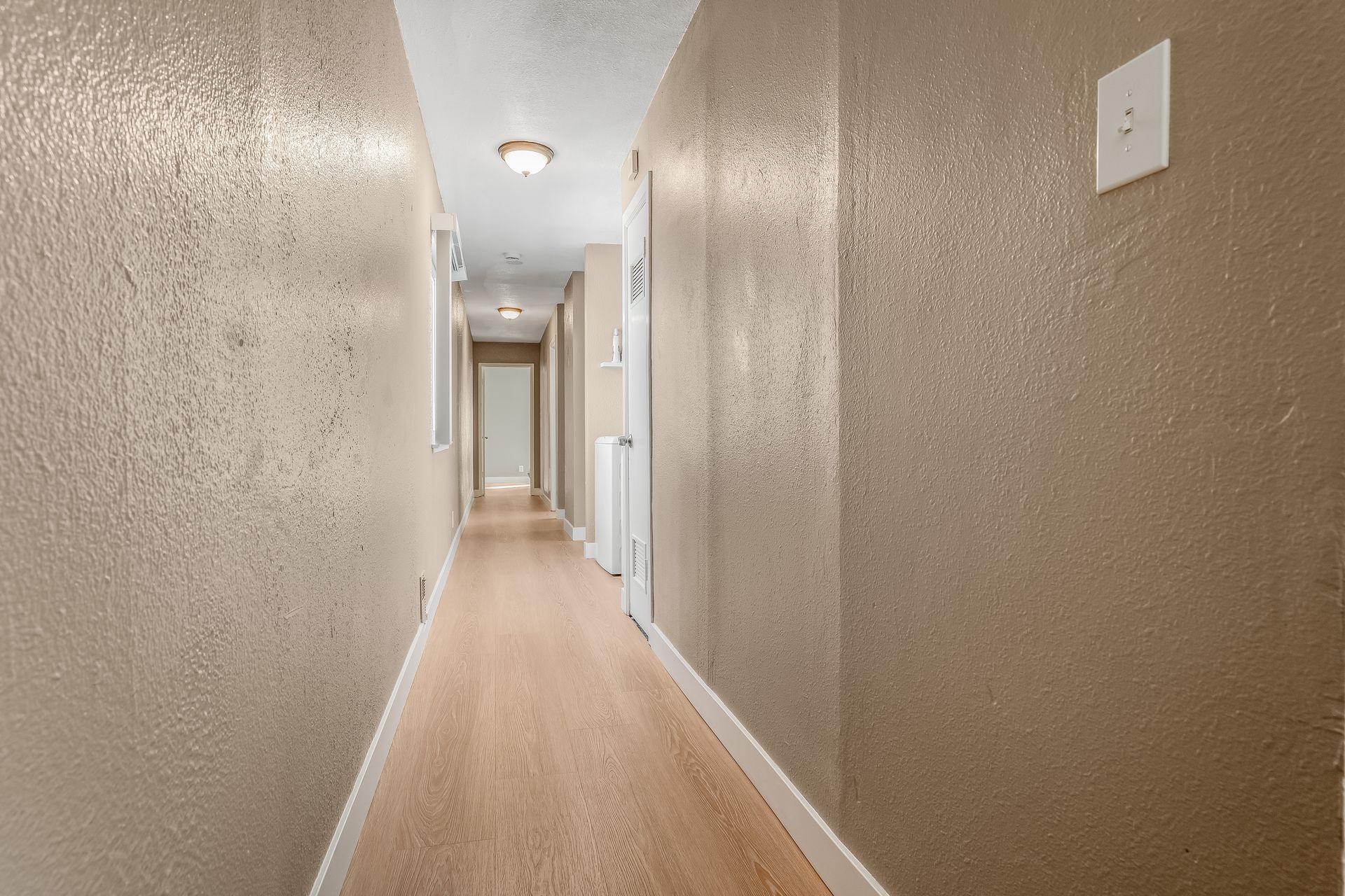 A long hallway with brown walls and wooden floors in a house.