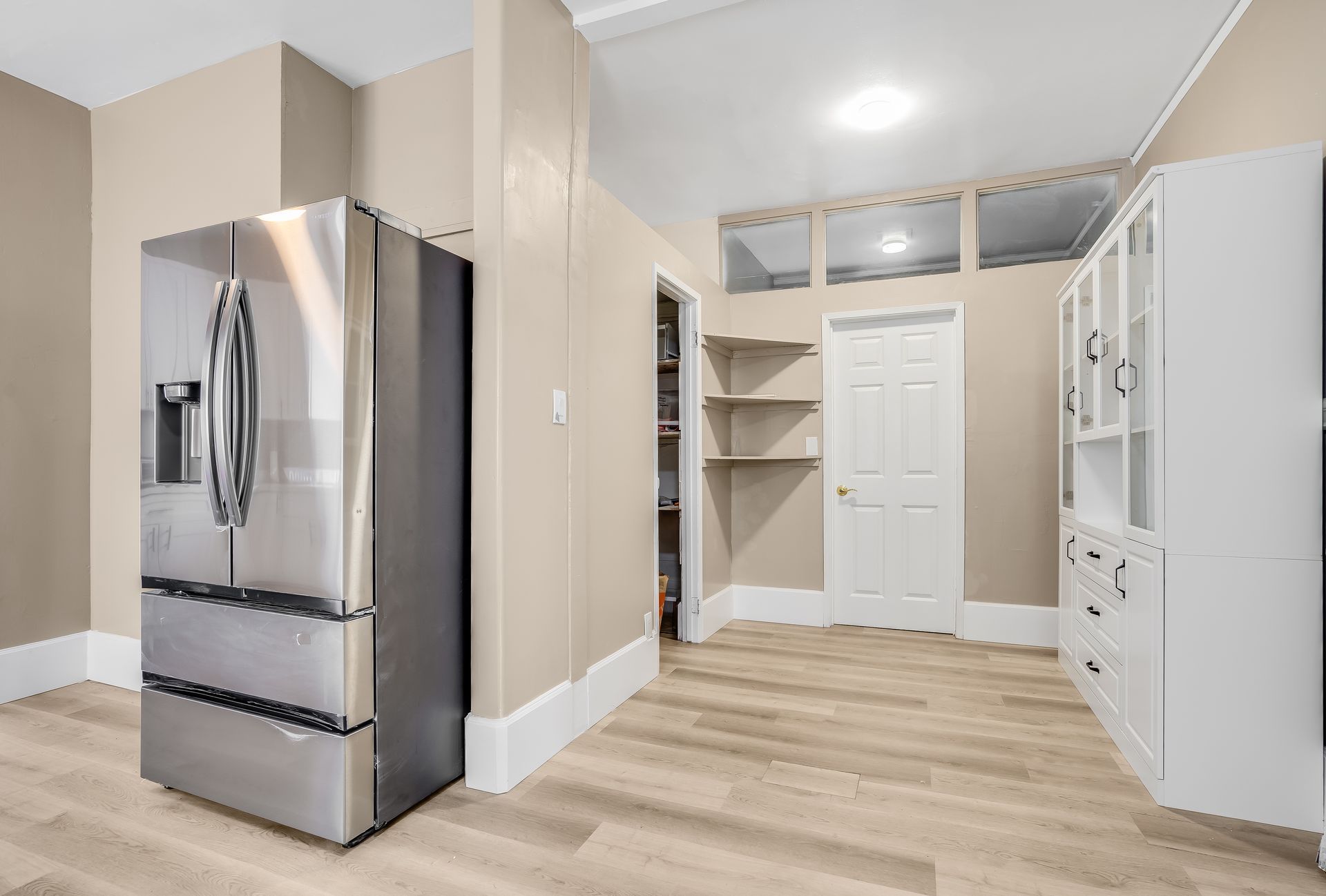 A stainless steel refrigerator is sitting in a kitchen next to a pantry.