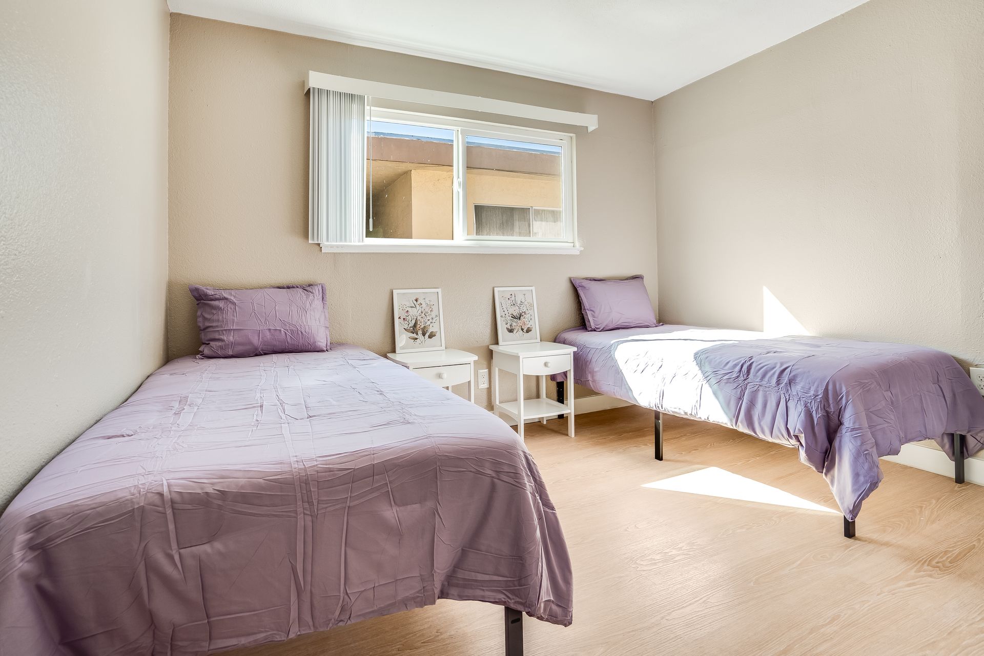 A bedroom with two twin beds and a window.