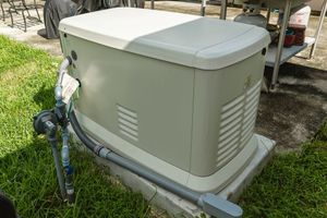 A generator is sitting on top of a concrete base in the grass.