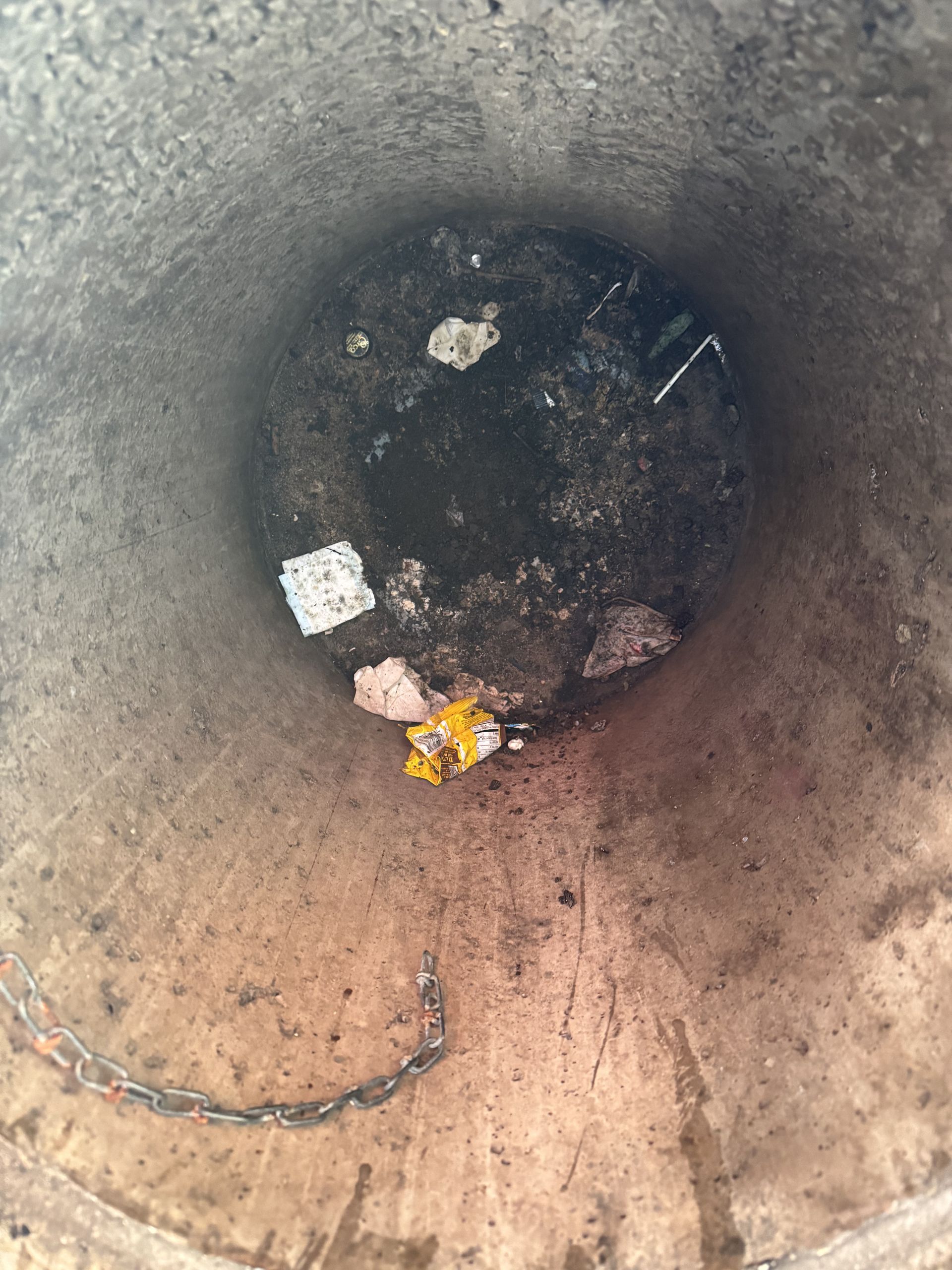 A filthy garbage bin in front of a retail building